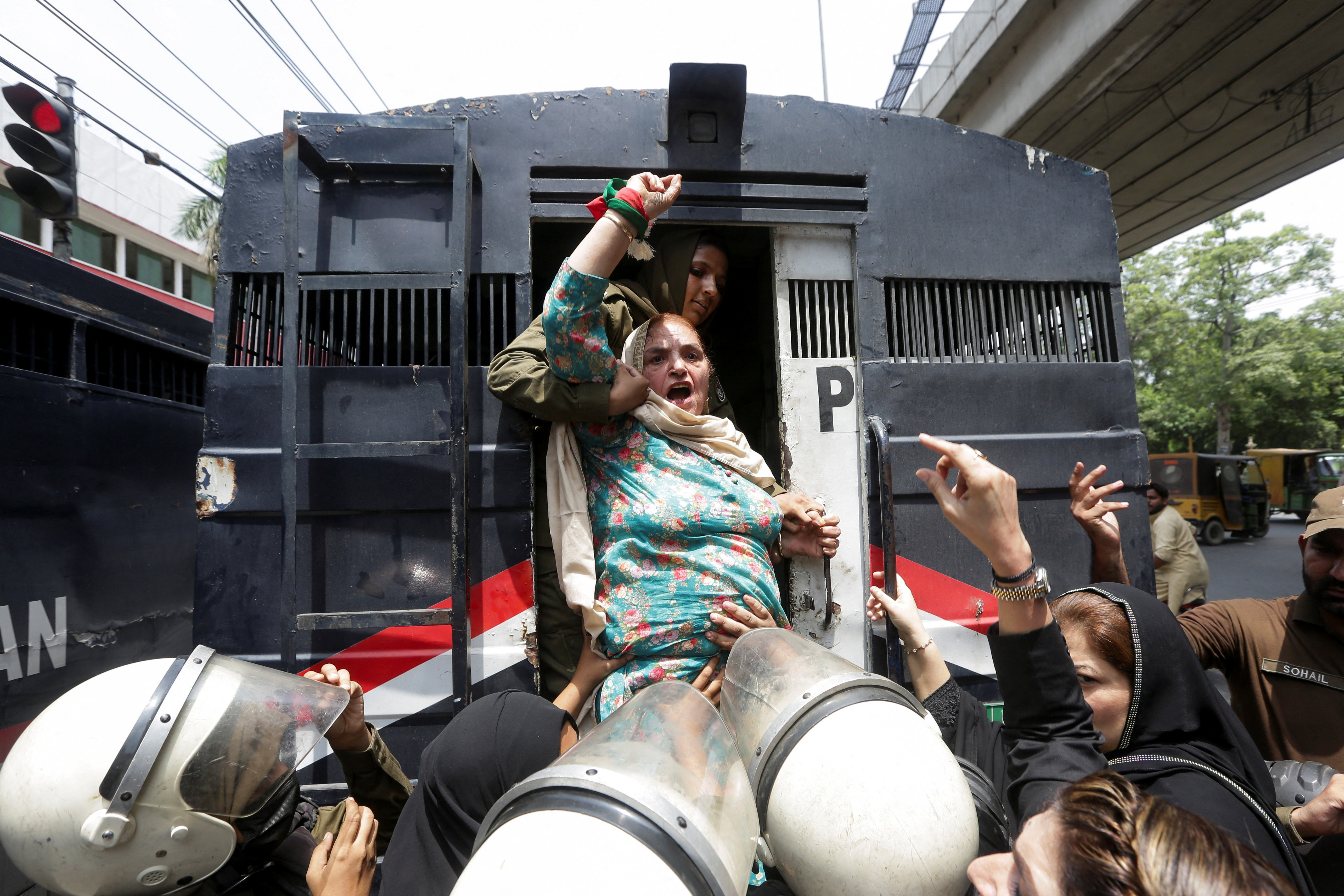 A woman chants while being detained by police officers during a protest.