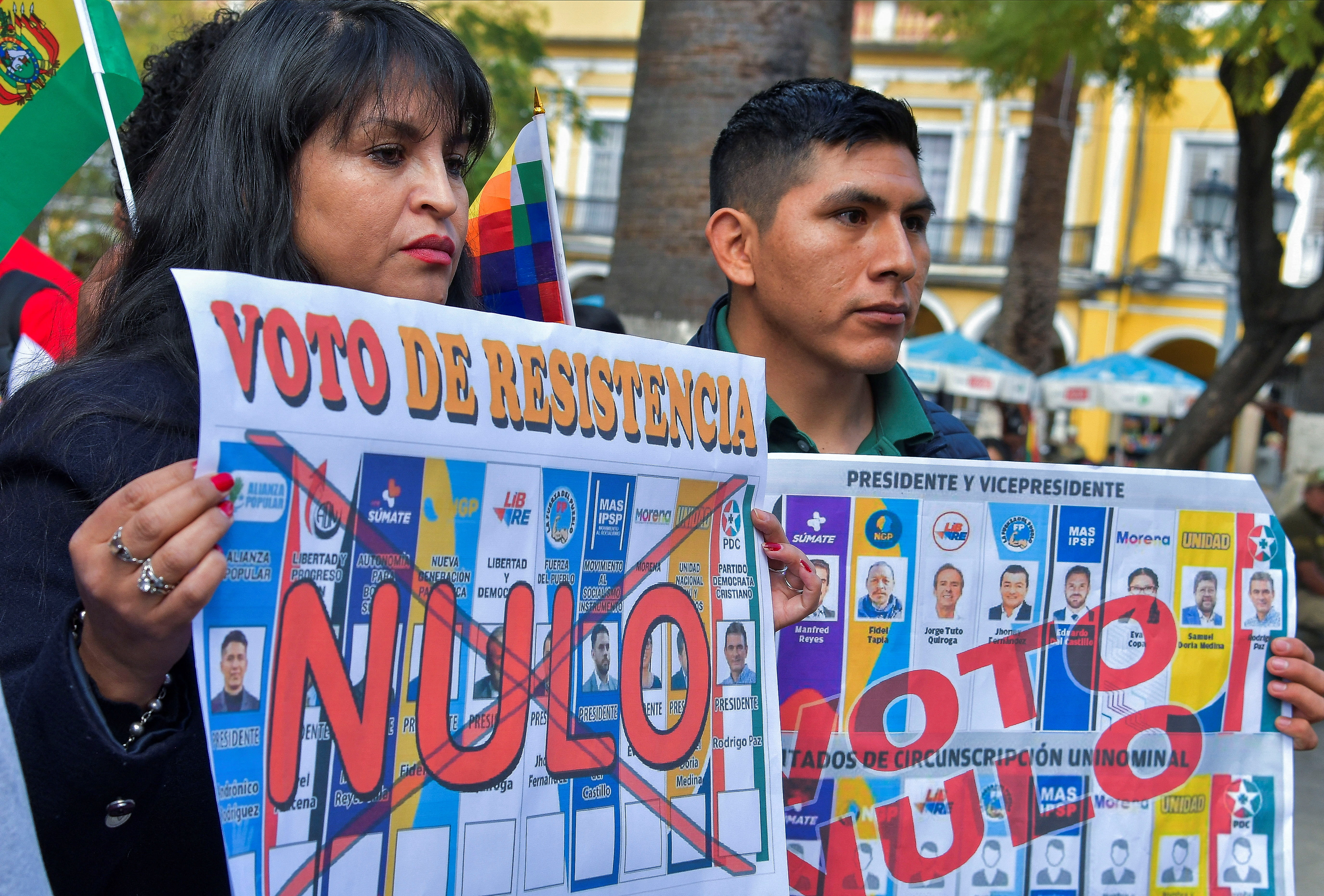 Supporters of Evo Morales hold up posters that show a ballot crossed out and the word "Nulo."