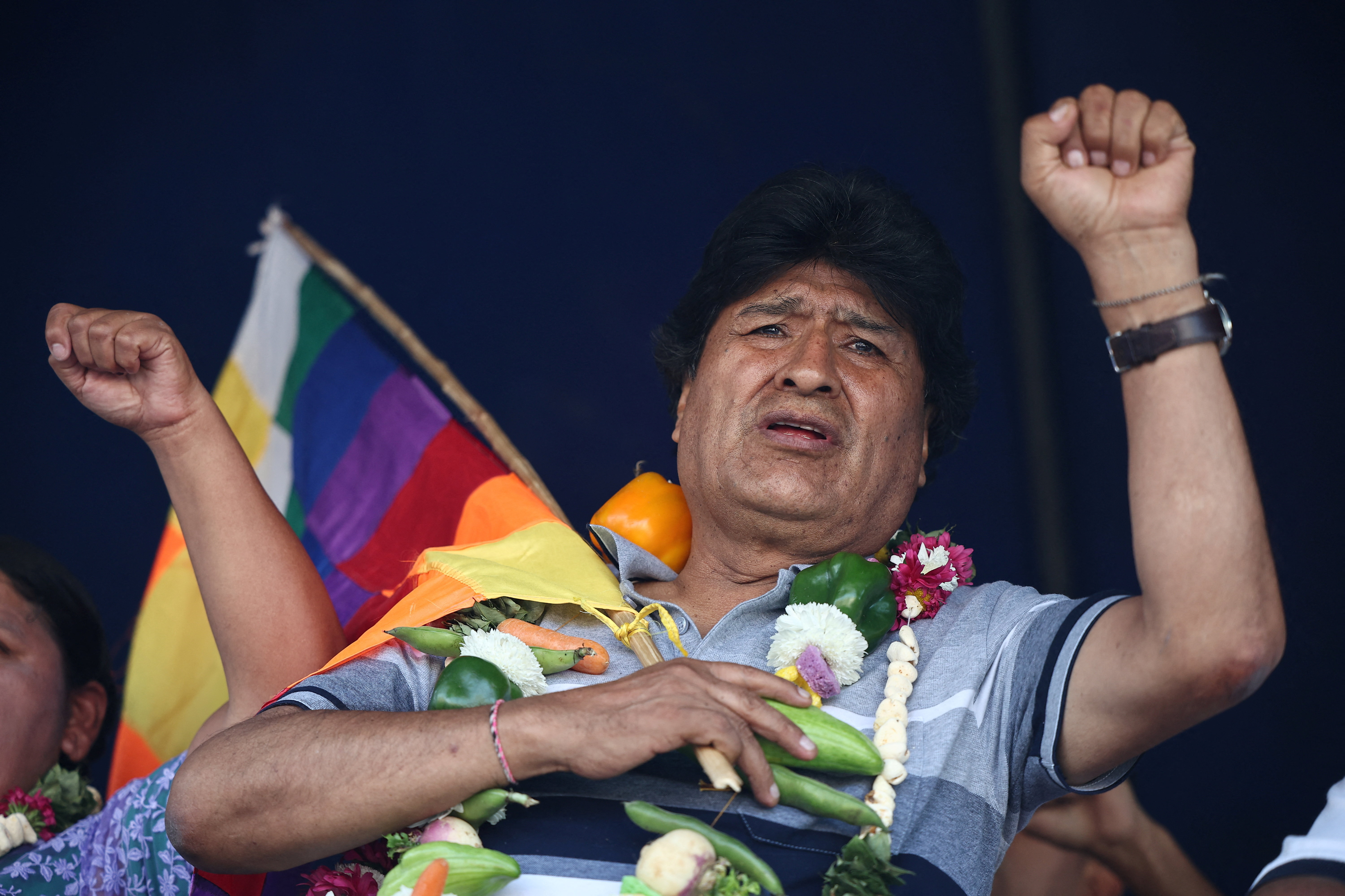 Emo Morales carries a flag and raises a fist into the air.