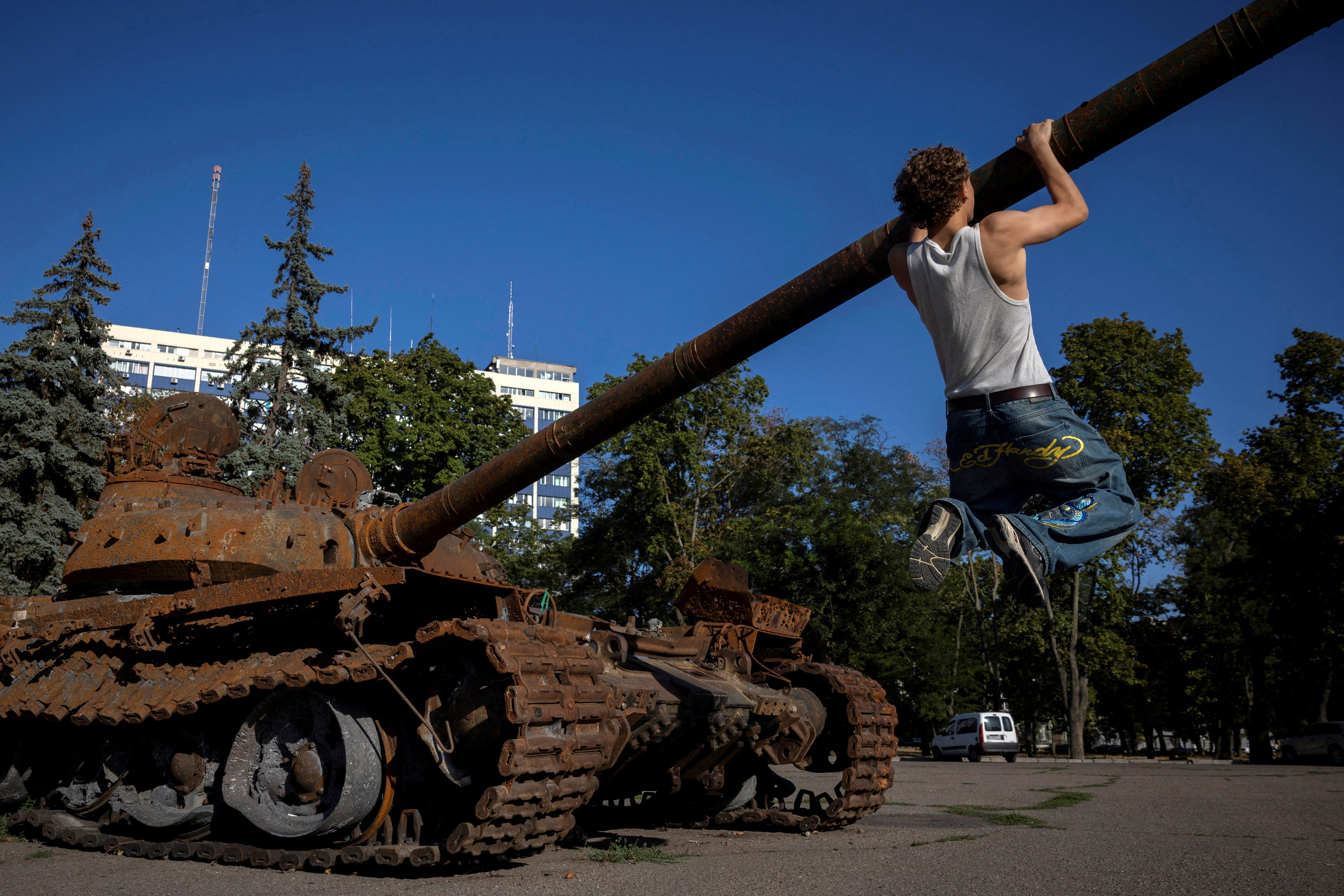 A man pulls himself up on the barrel of a captured Russian T-72 tank on display, amid Russia's attack on Ukraine, in the port city of Odesa, Ukraine August 12, 2025. REUTERS/Thomas Peter TPX IMAGES OF THE DAY