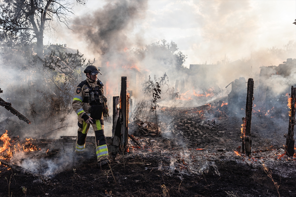 a fireman walks through the burned remains of a house in thick smoke