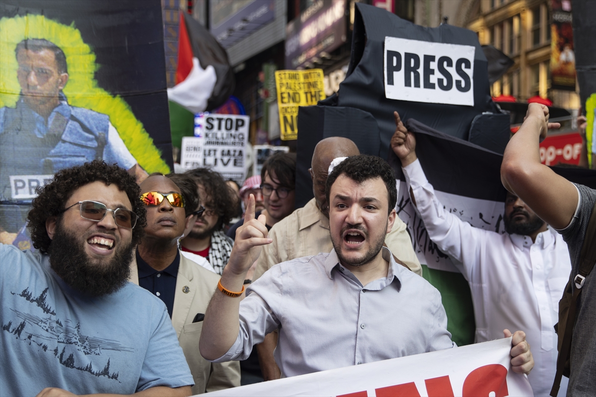 people hold large Palestinian flags and photos of journalists wearing press vests at a protest