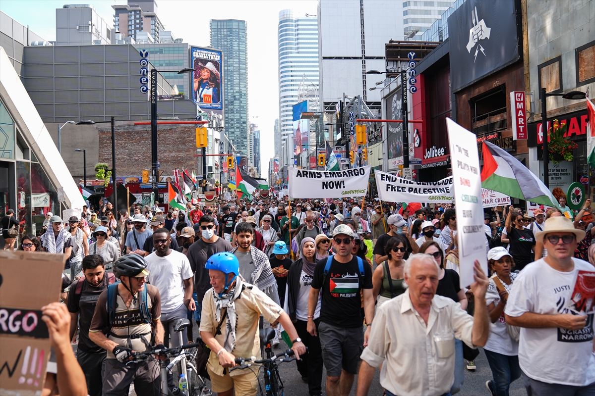 people hold banners and palestinian flags at a protest in a city centre