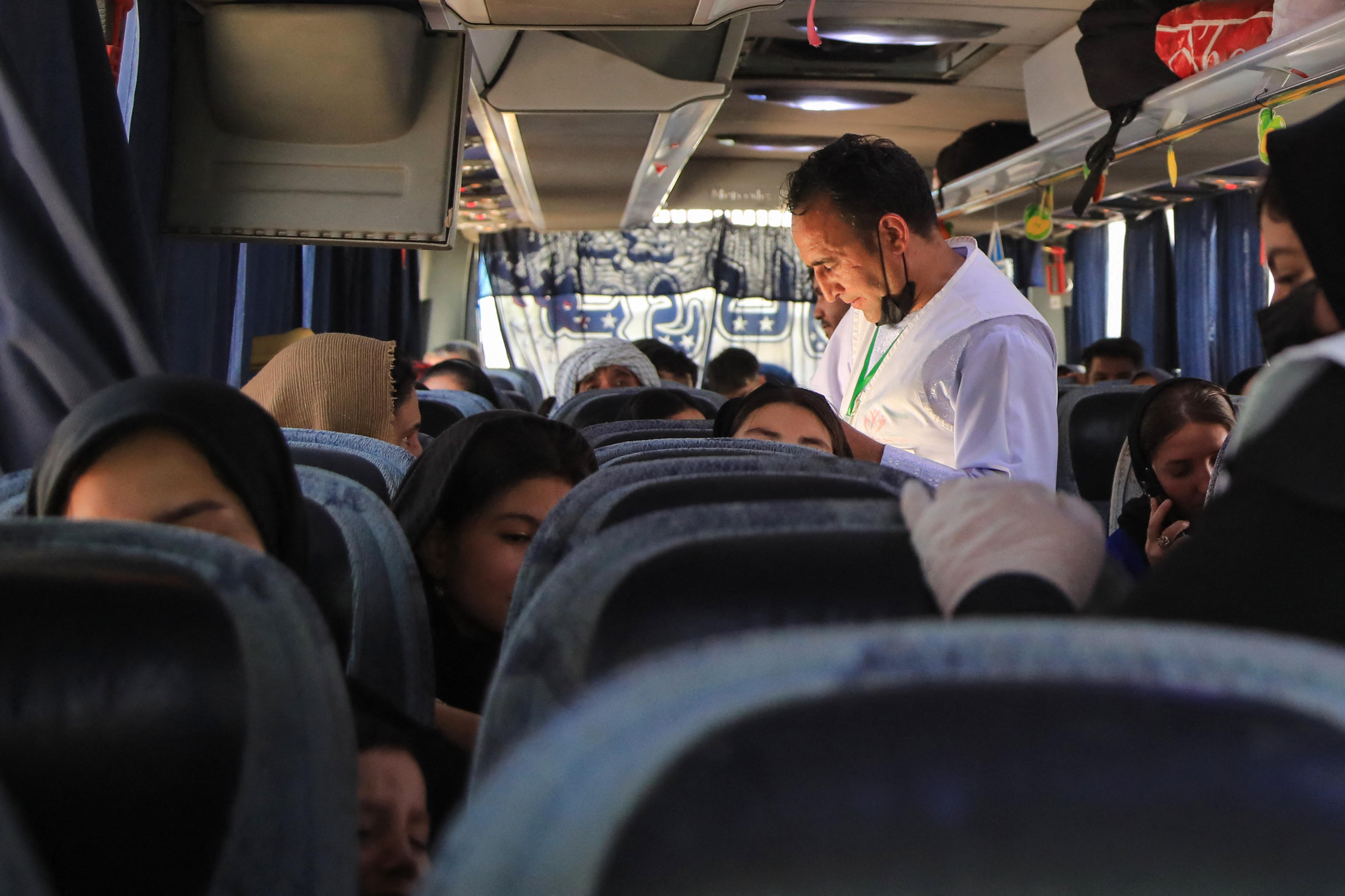 Abdul Qadir Salehi (C), an Afghan volunteer, checks a name list of the newly arrived Afghan migrants deported from Iran, inside a bus at the Islam Qala border crossing in Herat province, on July 24, 2025.