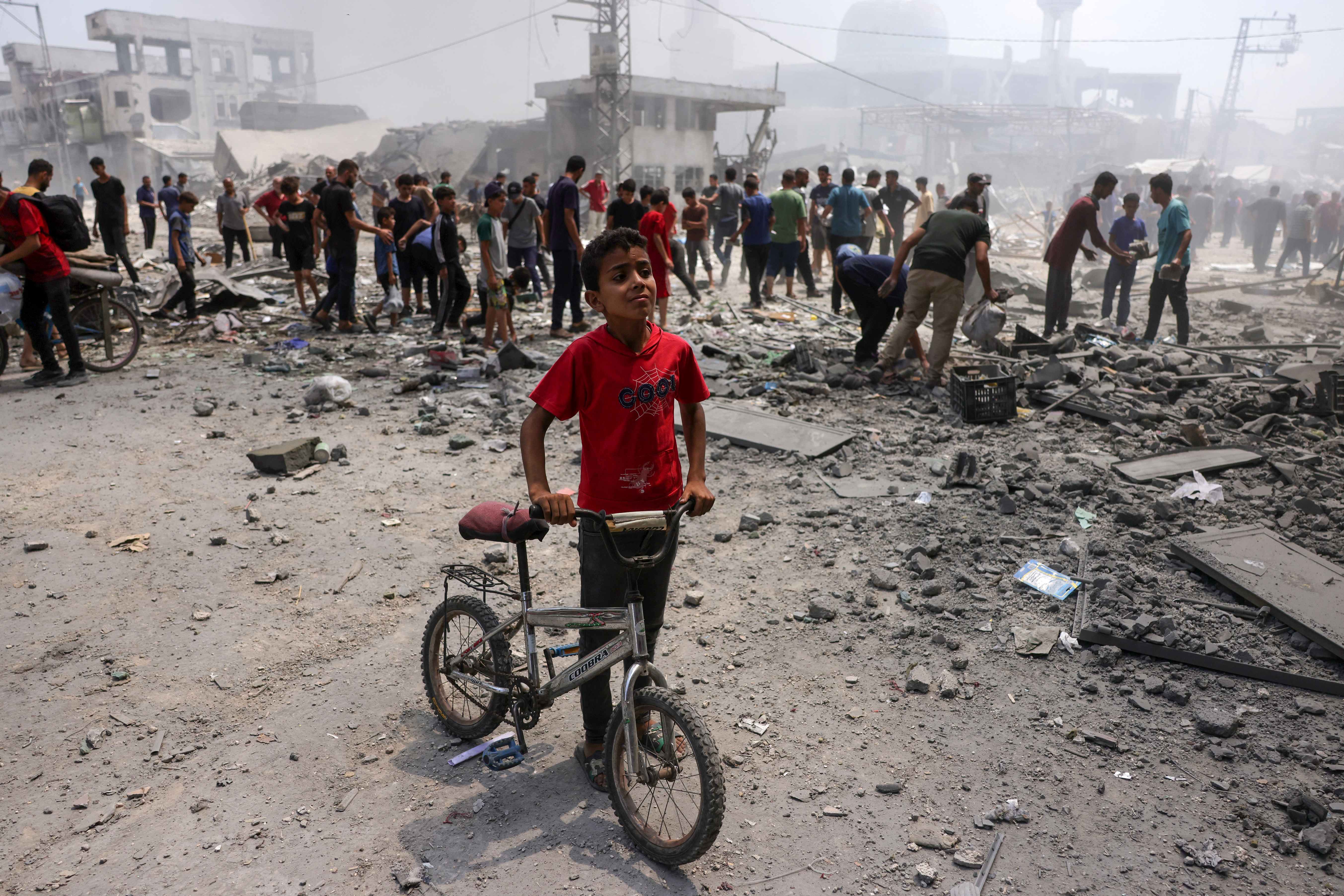 A young boy stands next to his bicycle as Palestinians check the devastation following an Israeli strike that hit Gaza City's southern al-Zeitoun neighbourhood