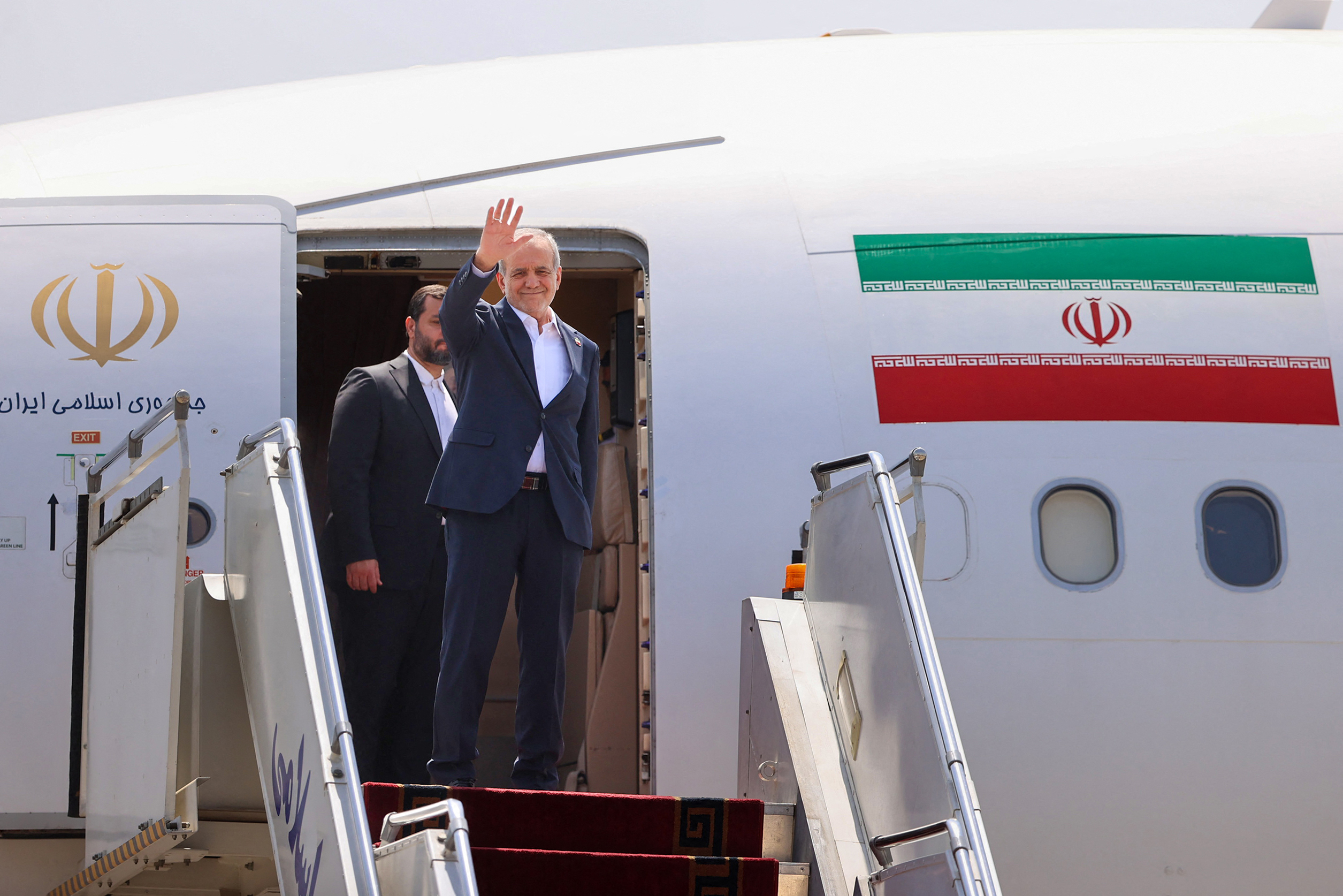 Iran's President Masoud Pezeshkian waves as he boards a plane at Tehran's Mehrabad Airport