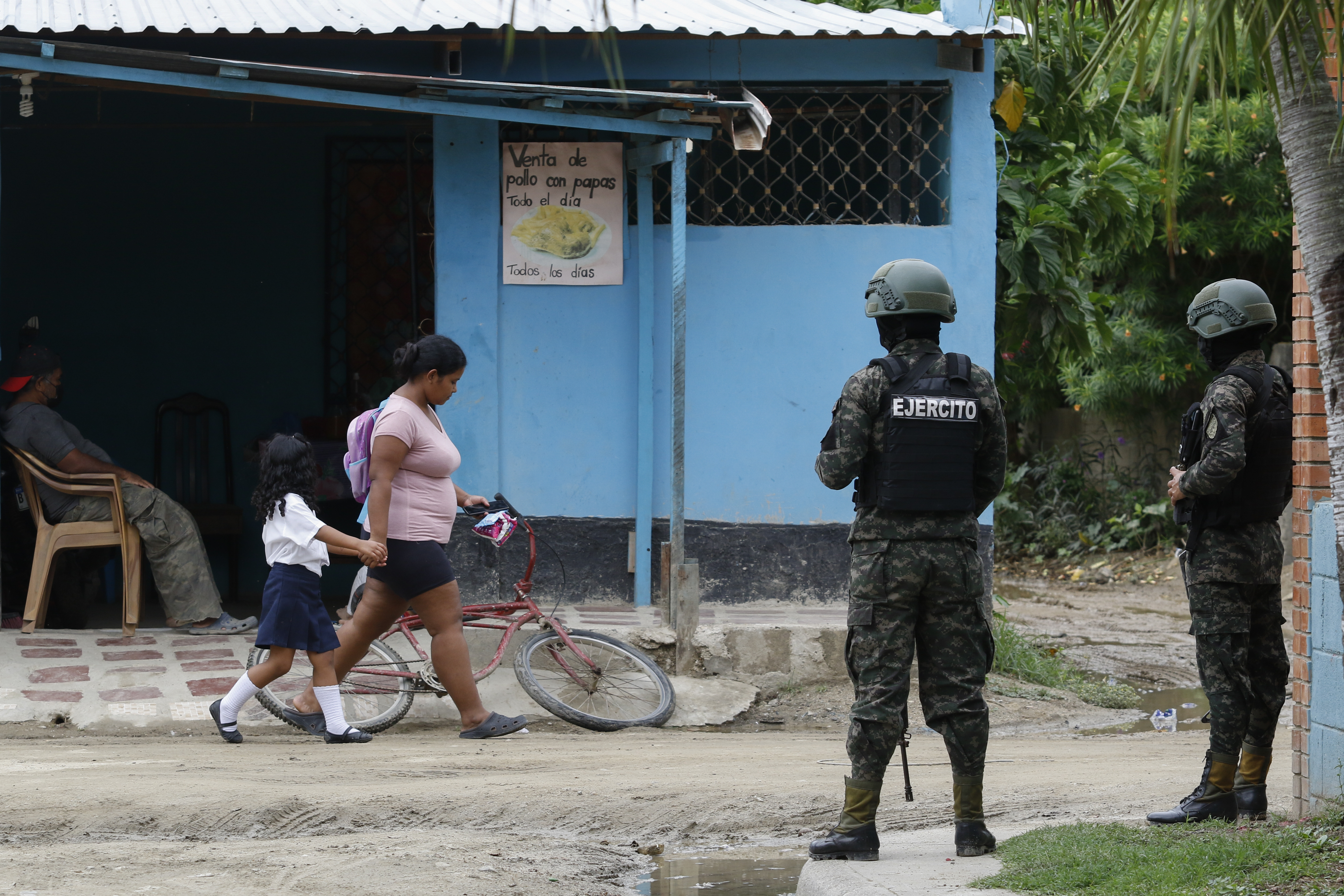 Two soldiers in San Pedro Sula, Honduras, watch two young people walk by in a neighbourhood.