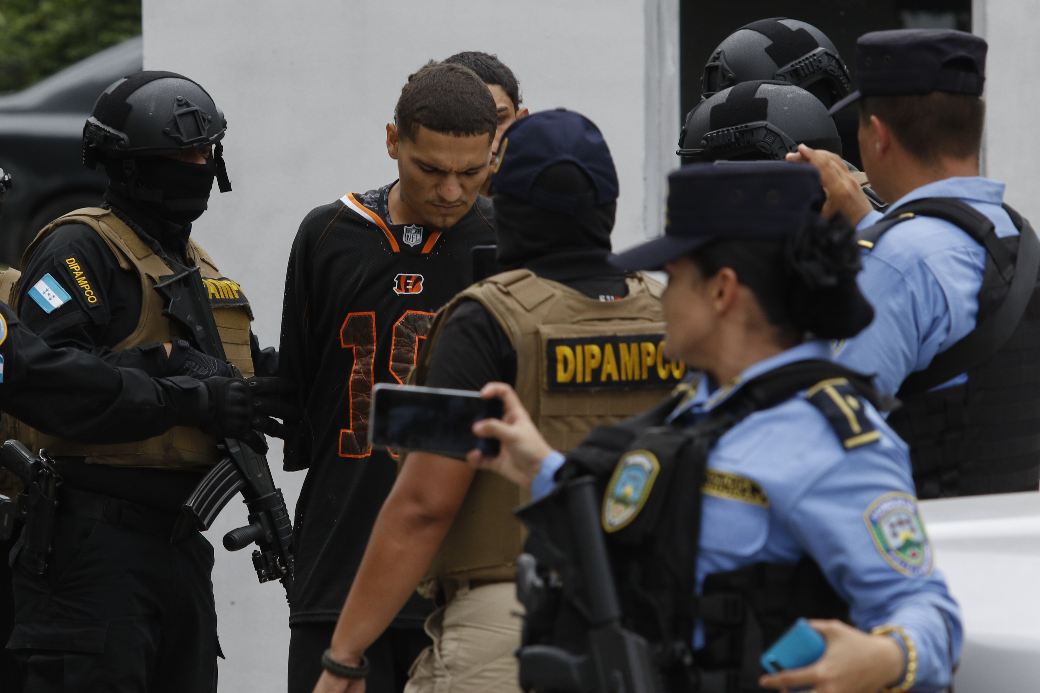 Members of DIPAMPCO surround a suspect in an NFL jersey.