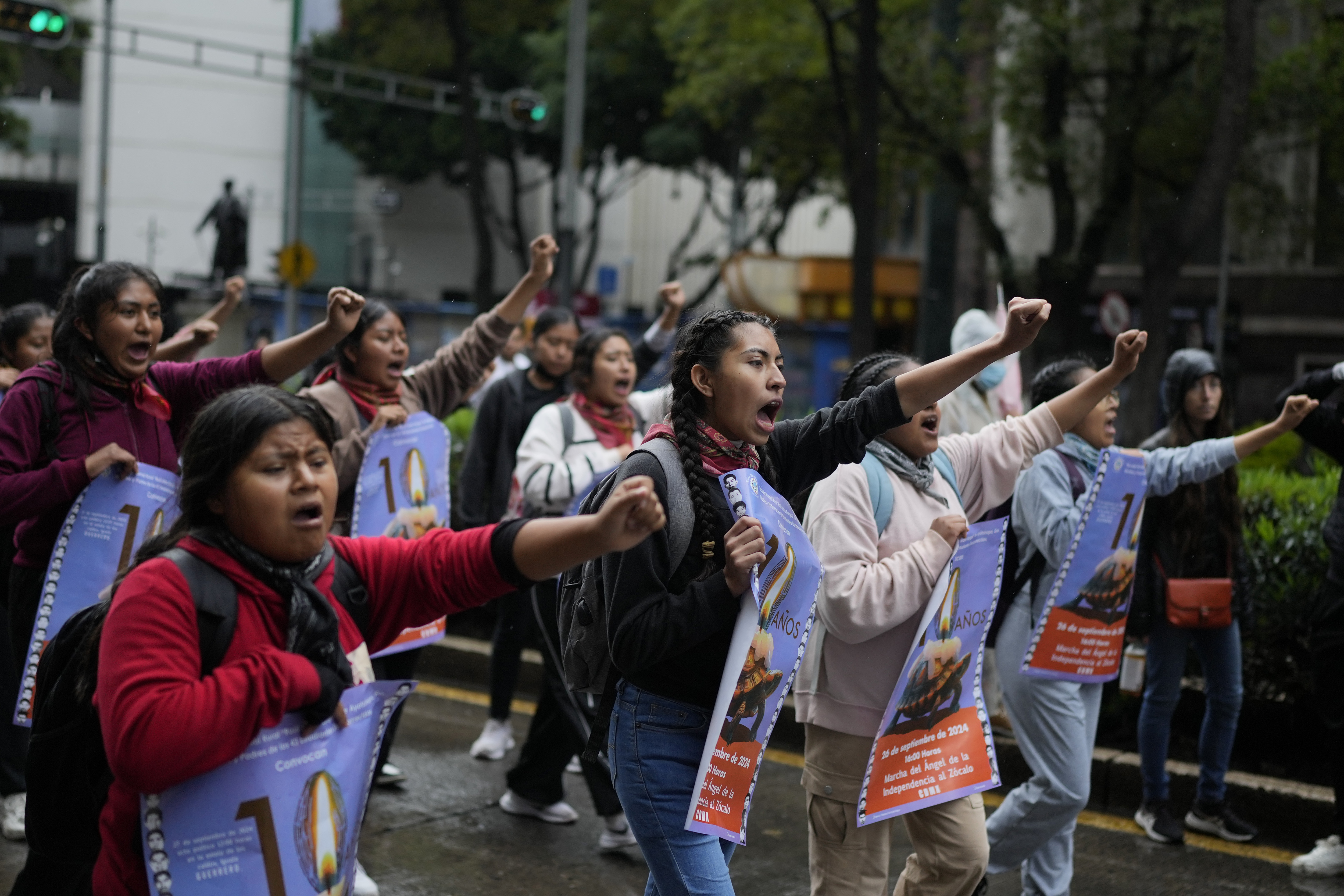 Students march with their hands raised in a fist through the streets of Mexico.