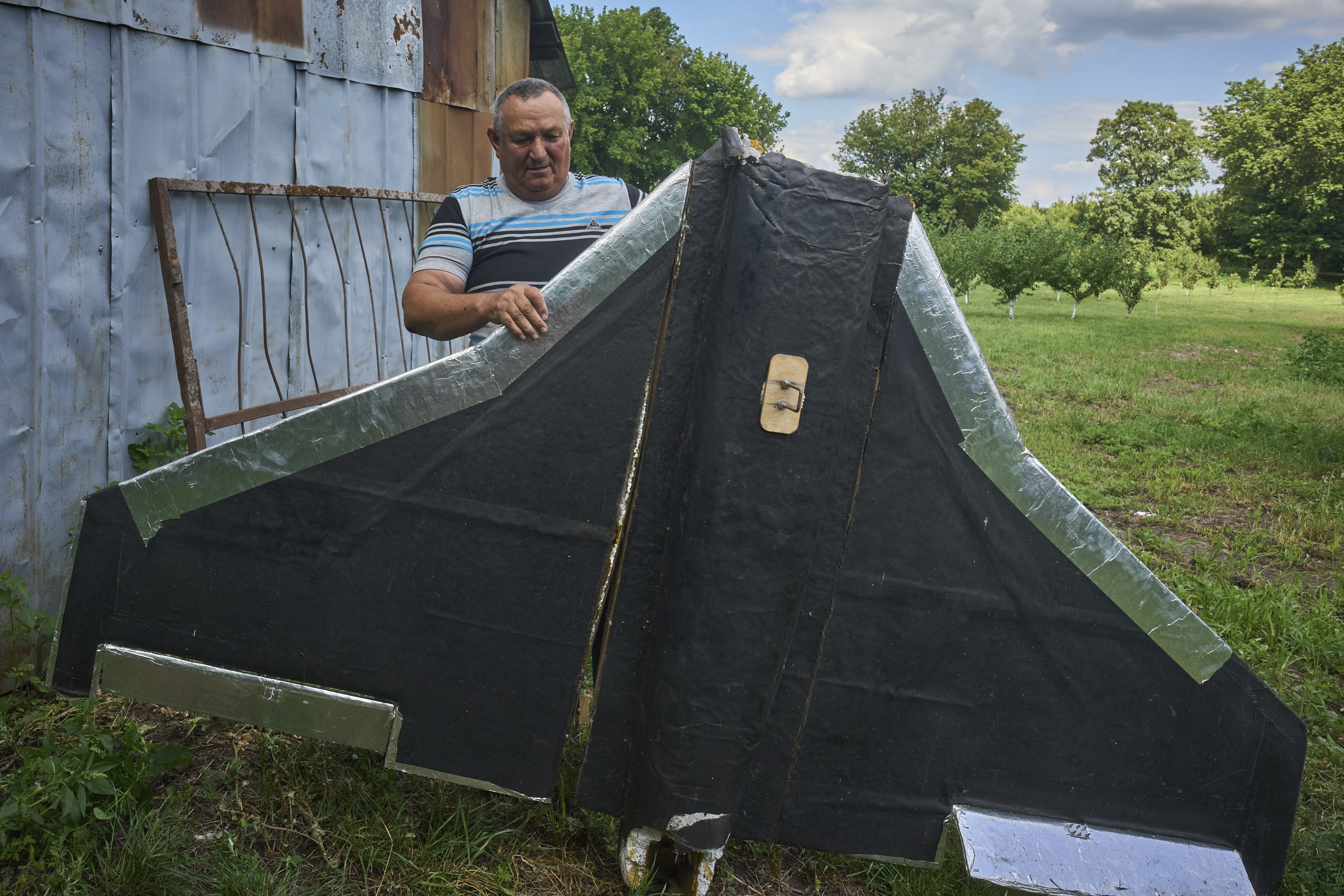 Victor Tsvik, an owner of a private farm, shows a fragment of a Russian drone that fell down on his field in Kyiv region, Ukraine, Sunday, Aug. 3, 2025. (AP Photo/Efrem Lukatsky)