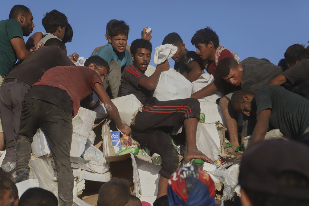 Palestinians struggle to get food and humanitarian aid from the back of a truck as it moves along the Morag corridor near Rafah, in the southern Gaza Strip, Monday, Aug. 4, 2025. (AP Photo/Mariam Dagga)
