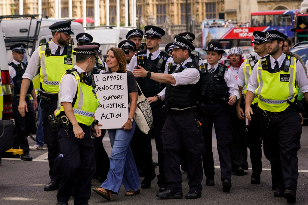 police lead away a woman holding a sign saying I oppose genocide I support Palestine Action