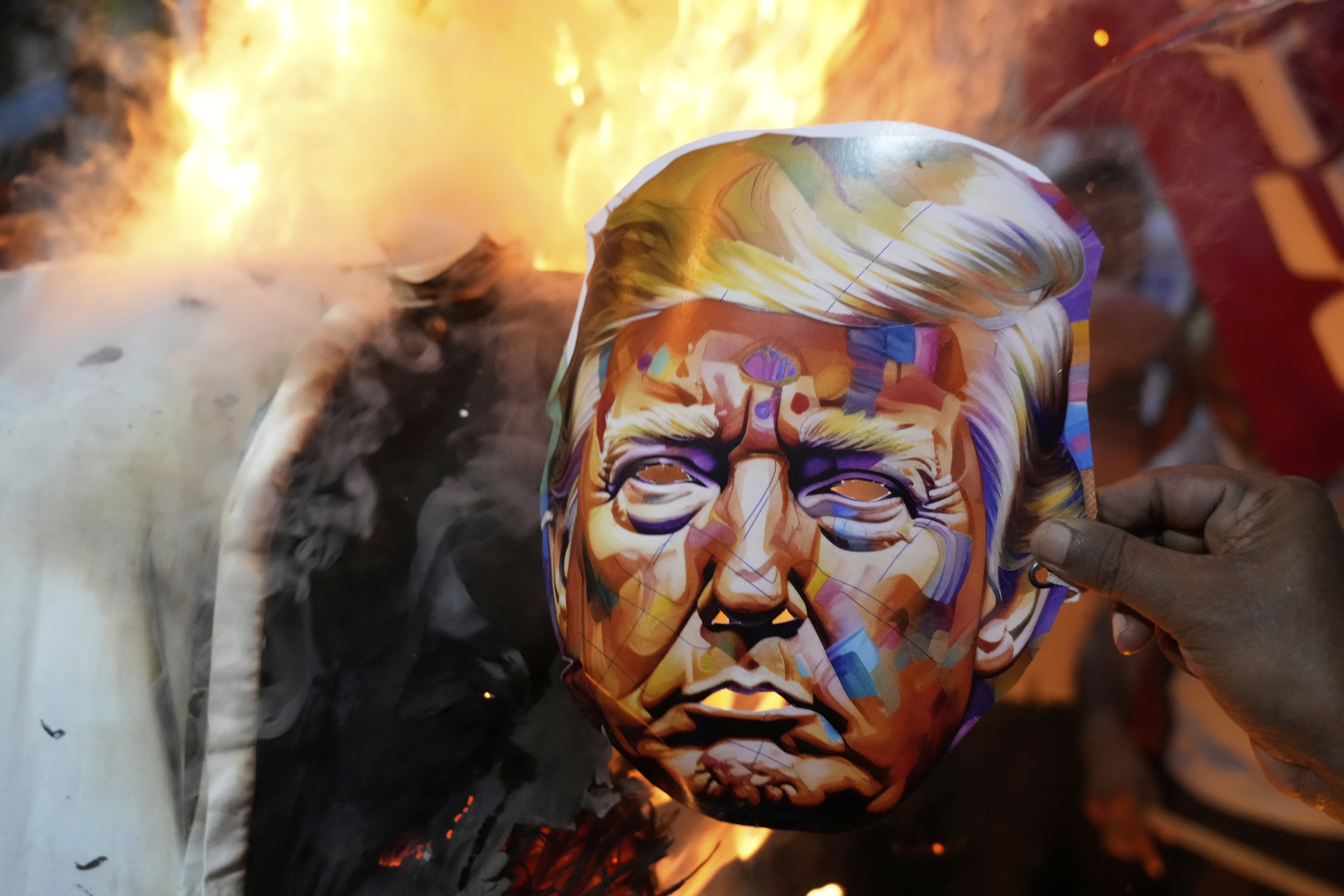Activists in India burn an image of Trump's face.