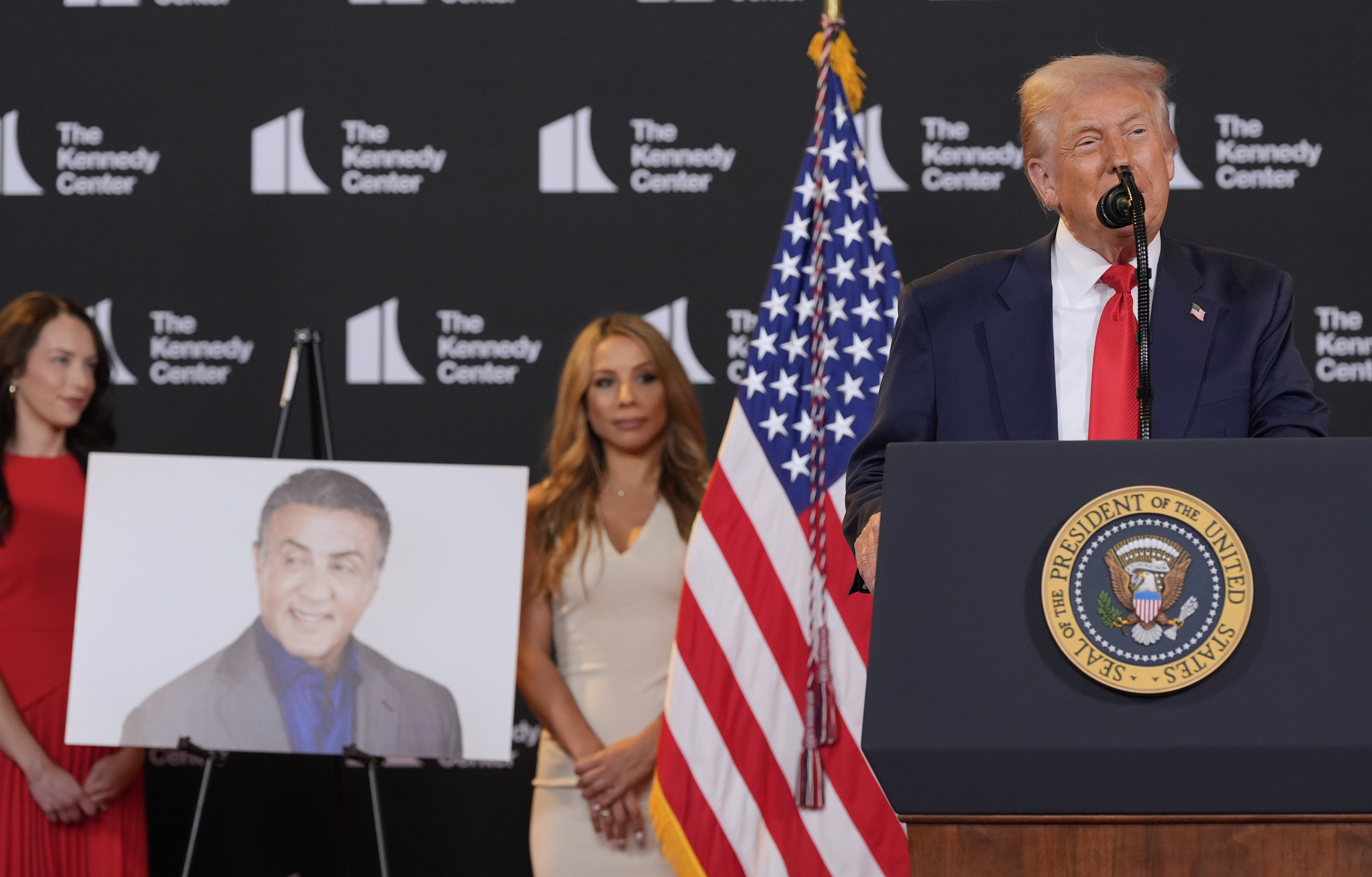 Trump stands in front of a photo of Sylvester Stallone at the Kennedy Center