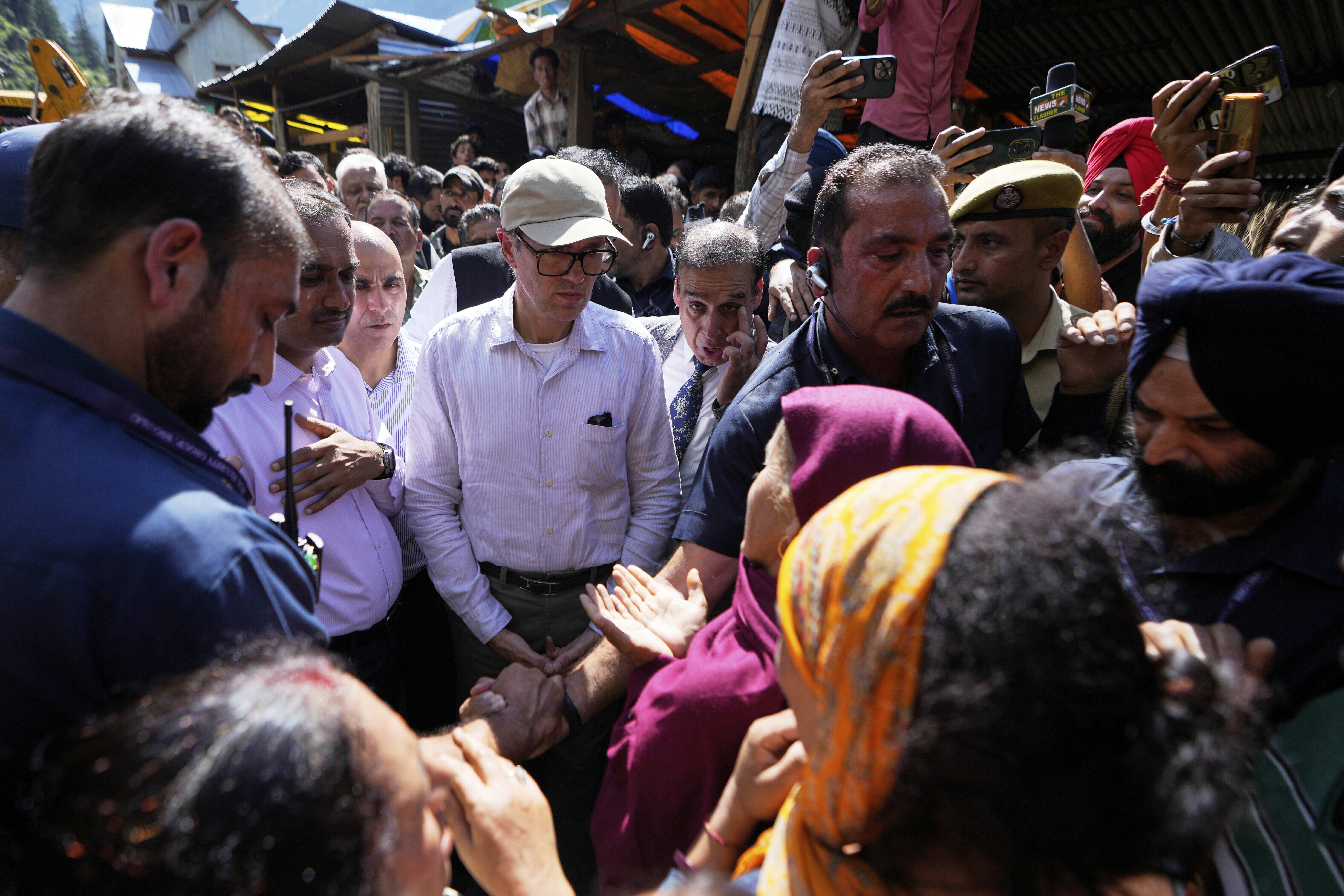 Chief Minister of Jammu and Kashmir, Omar Abdullah, in white shirt and a cap, speaks to people affected by Thursday's flash floods in Chositi village, Kishtwar district, Indian-controlled Kashmir, Saturday, Aug. 16, 2025. (AP Photo/Channi Anand)