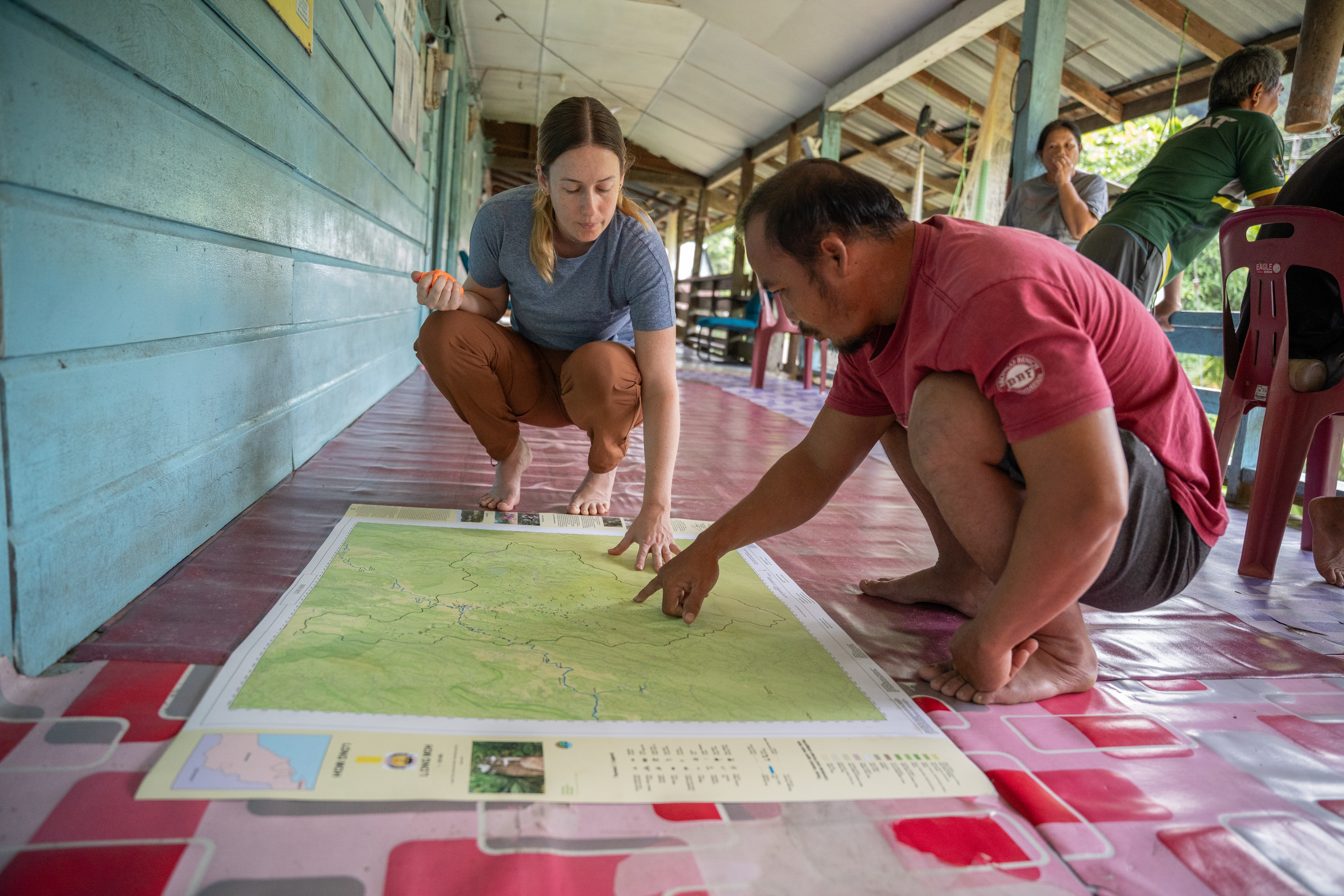Jessica Merriman from the Borneo Project inspects Long Moh community map with a member of Long Moh village [Izzy Sasada/Al Jazeera]