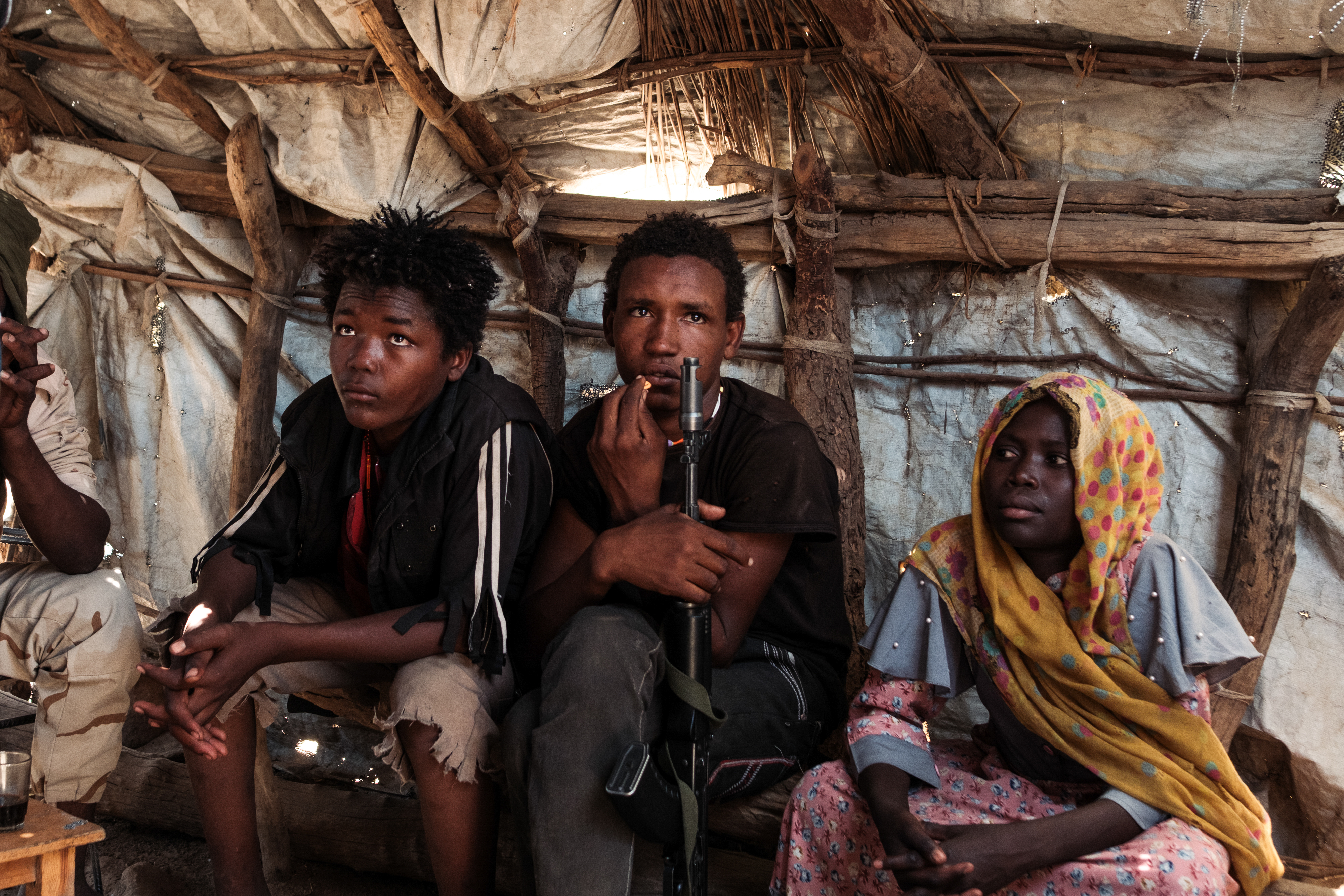 Two teenage members of the Rapid Support Forces sit in a cafe in Tongoli on April 22, 2025.