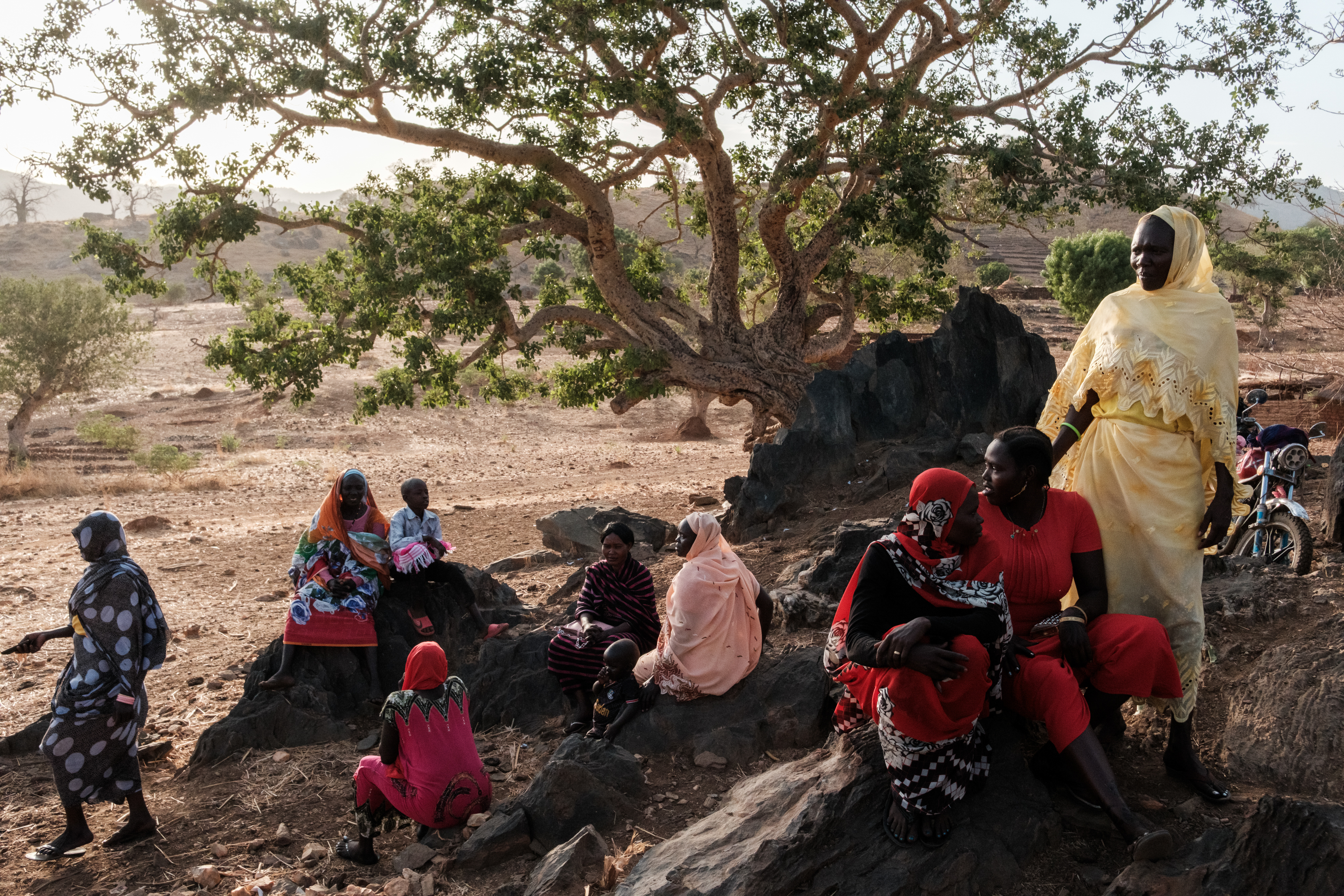 Women sit on rocks watching the giving of the dowry as part of a wedding celebration in Kauda on April 18, 2025. The wedding celebrations were going to be delayed with a famine during the last dry season stretching peoples resources the bride and groom who would usually pay for the wedding were no longer able to. The community came together so the wedding could still go ahead raiding what was needed for the dowry.