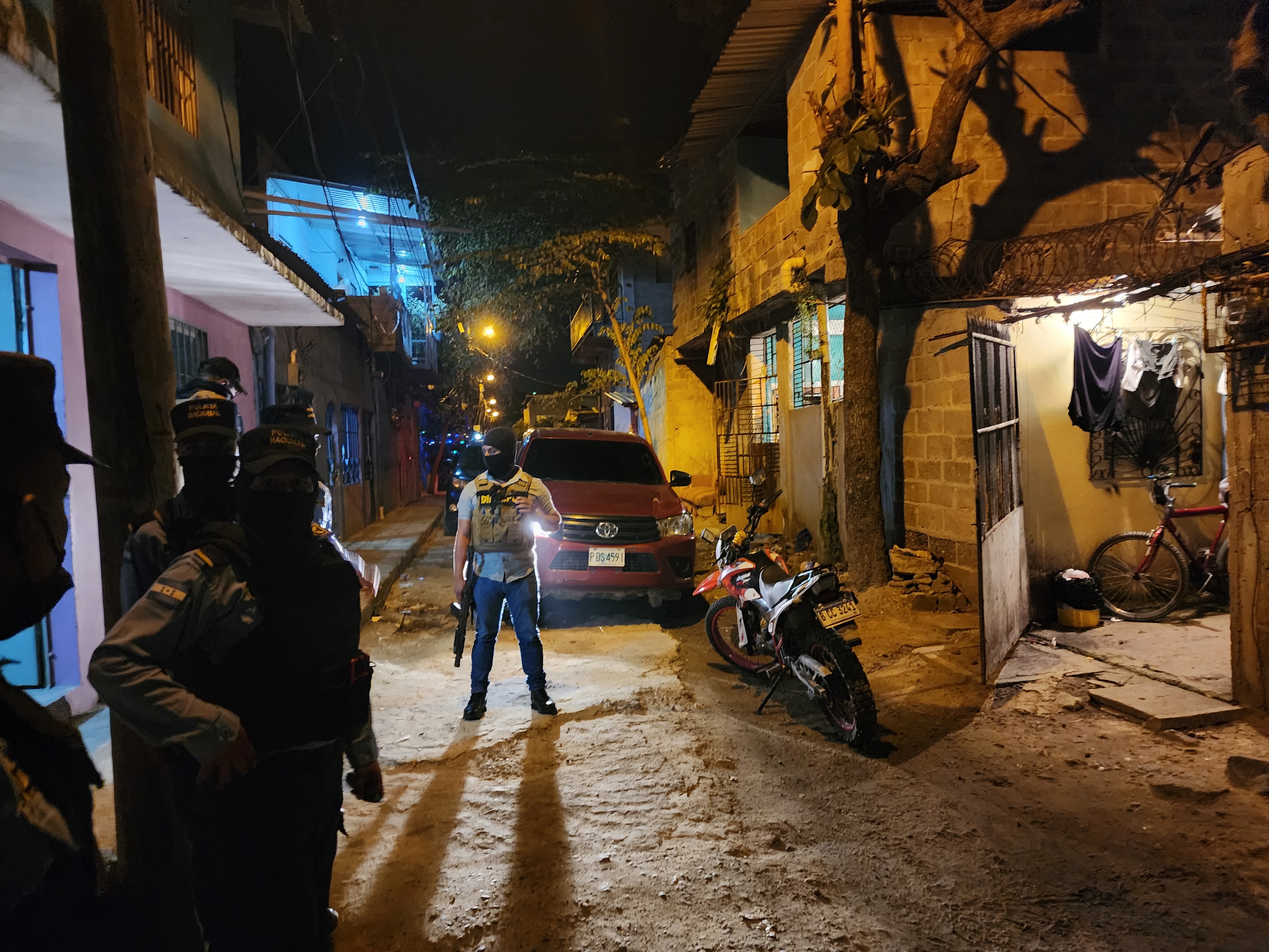 An armed DIPAMPCO member stands in a darkened road at night.