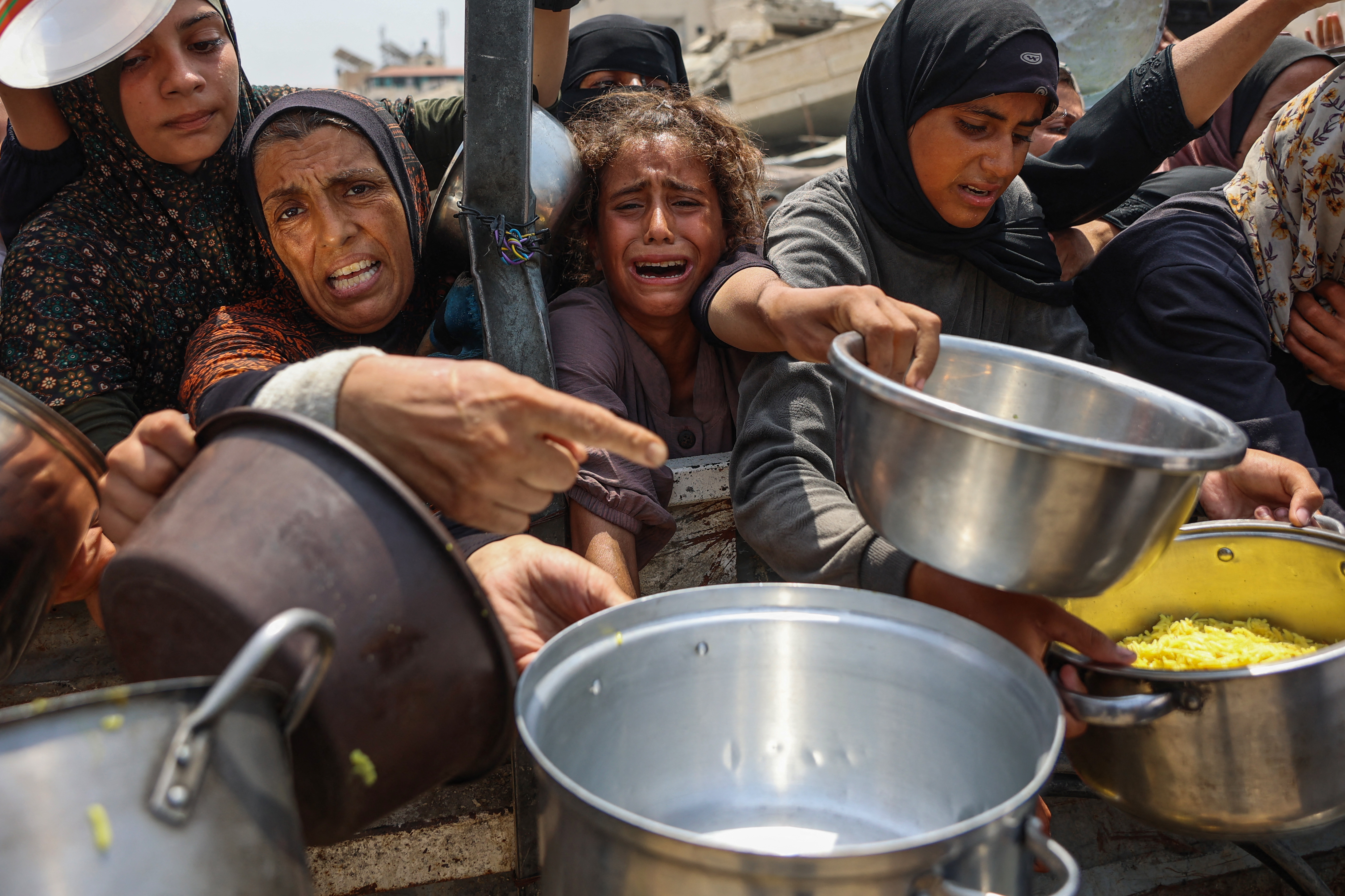 TOPSHOT - A Palestinian girl cries as she tries to receive cooked meals along with others from a food distribution center in Gaza City on August 13, 2025.