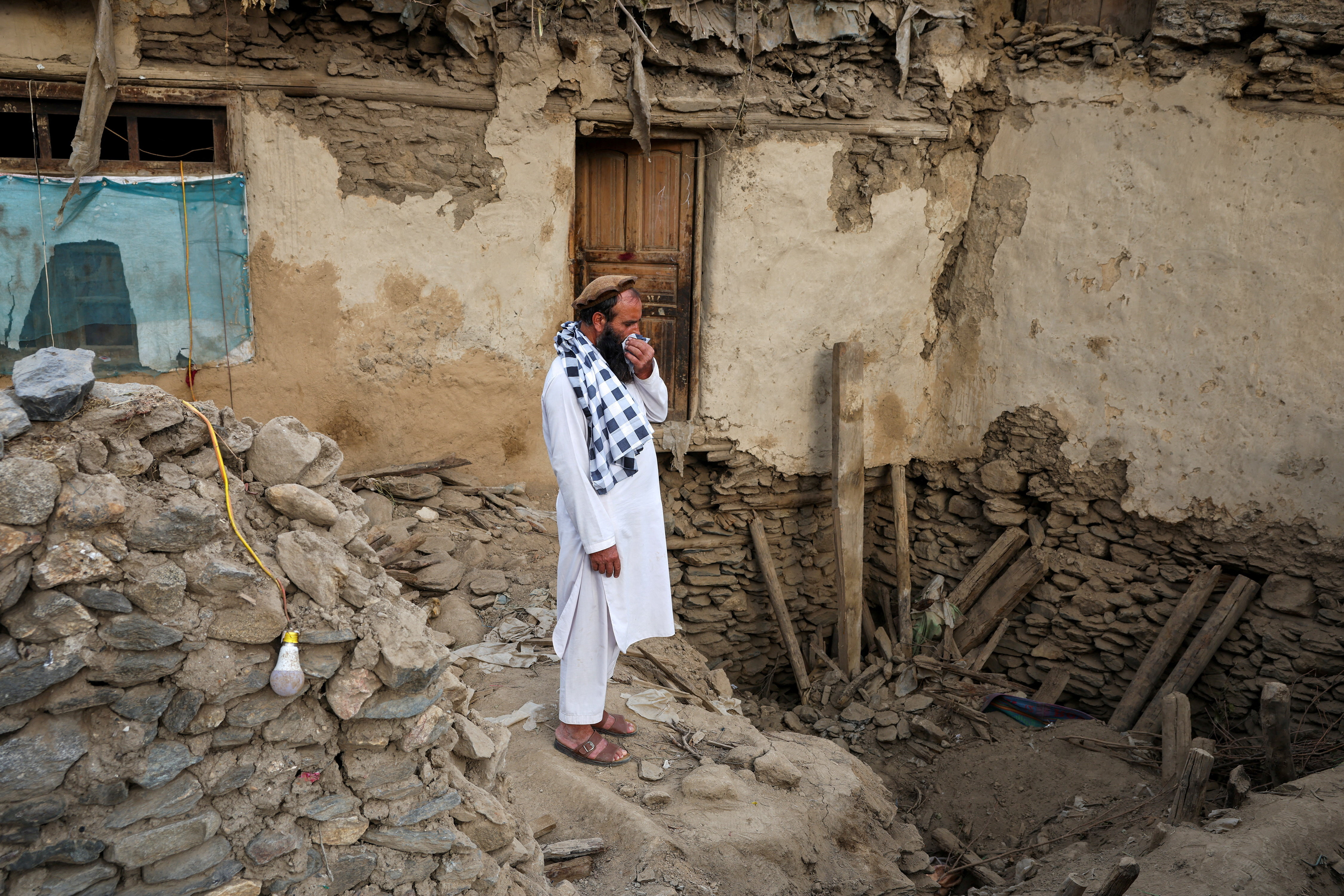 An Afghan man stands amid the rubble of a collapsed house.