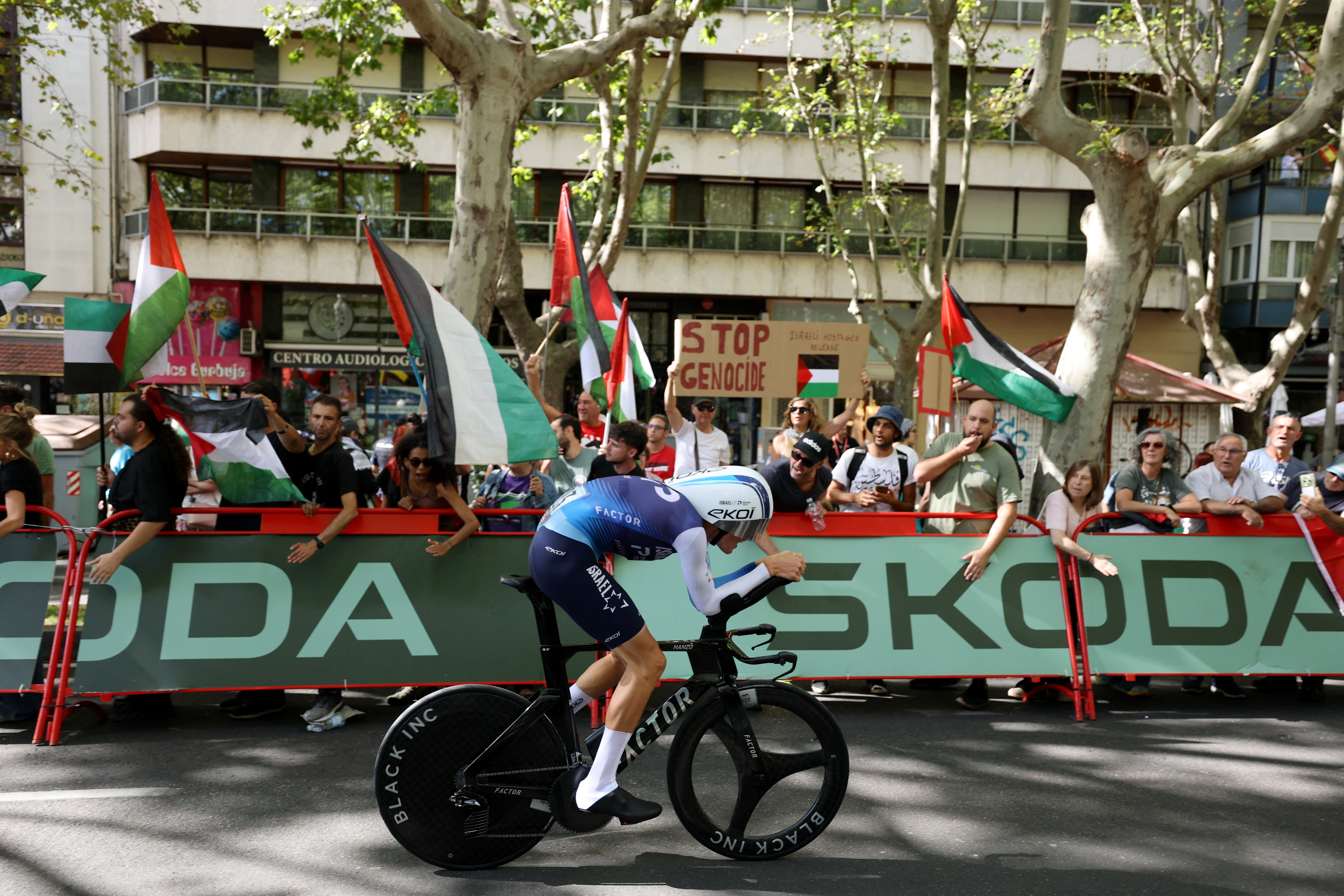 Cycling - Vuelta a Espana - Stage 18 - Valladolid to Valladolid - Valladolid, Spain - September 11, 2025 Israel - Premier Tech's Marco Frigo in action as pro-Palestine protestors are pictured in the background REUTERS/Juan Medina