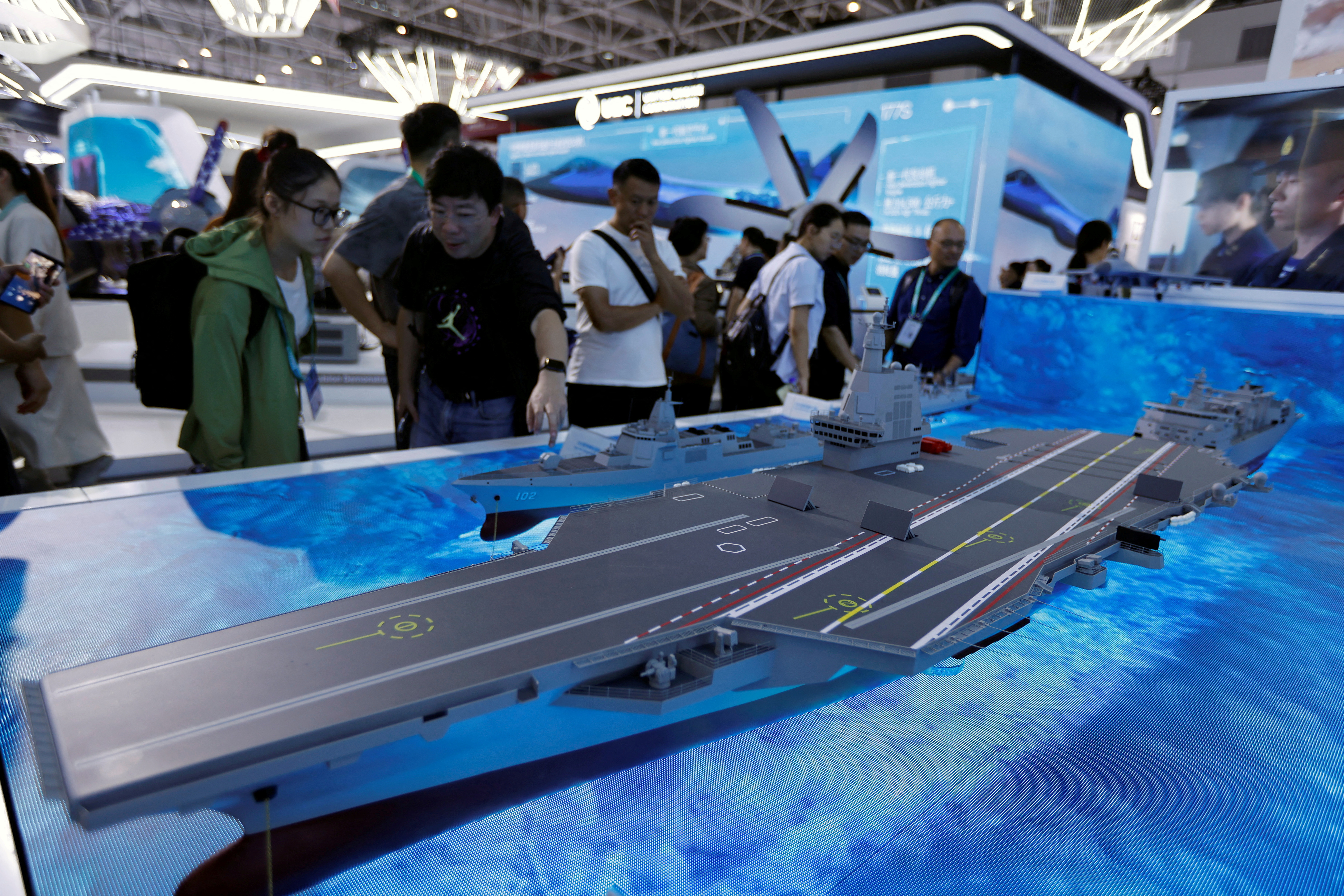 Visitors look at a model of the Fujian Type 003 aircraft carrier displayed at an exhibition.