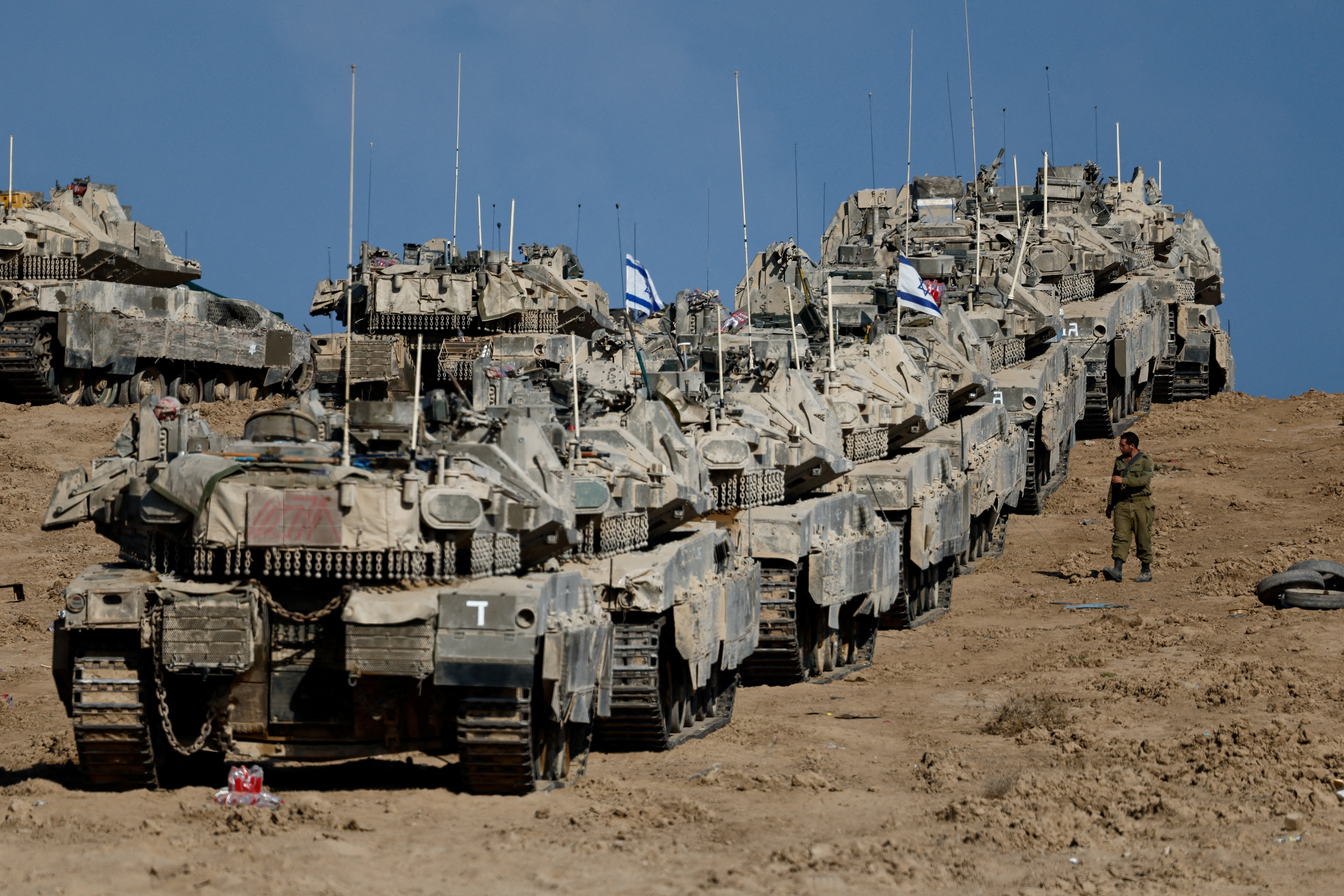 An Israeli soldier walks next to military vehicles near the border with Gaza