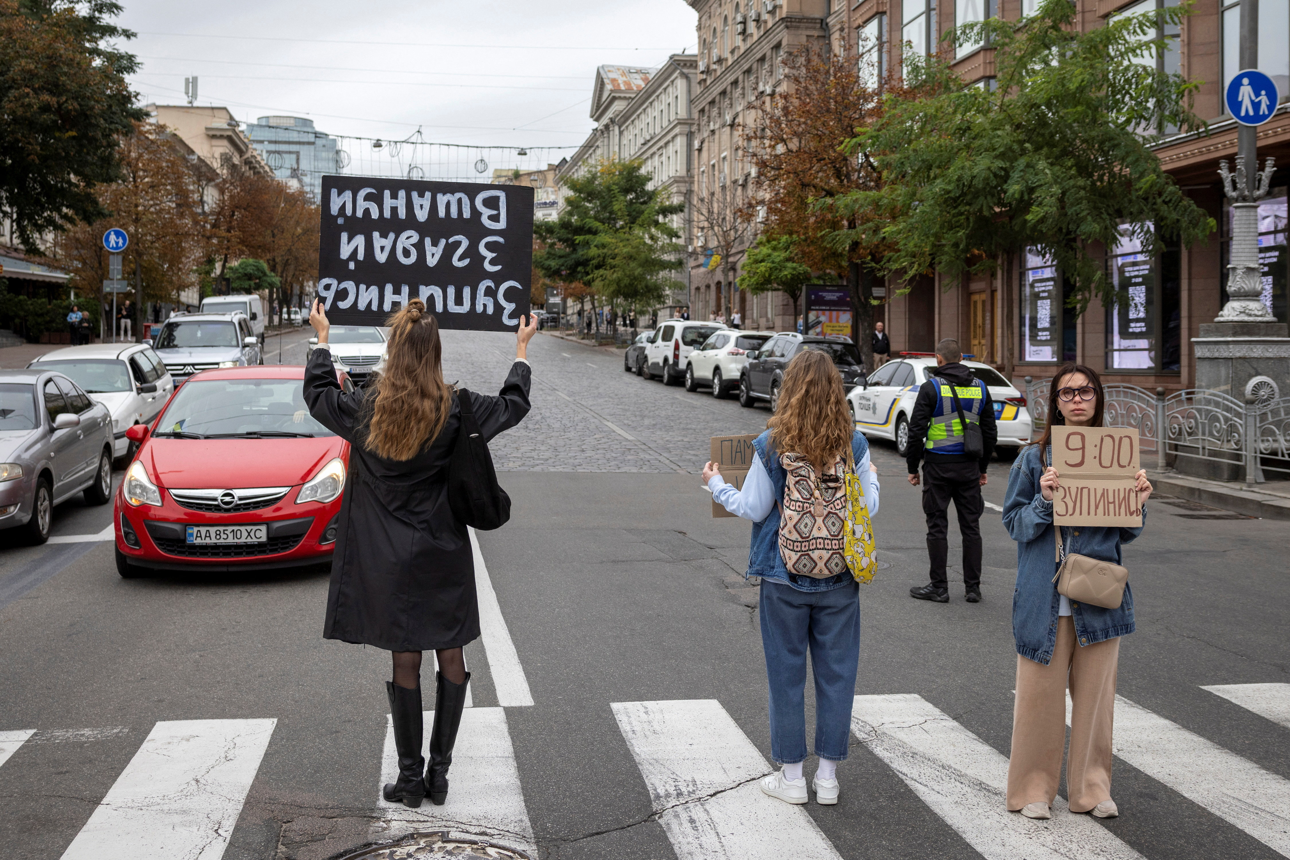People hold placards and drivers pause on Khreshchatyk Street to observe a minute of silence in honour of those who were killed during Russia’s attack on Ukraine, in Kyiv, Ukraine September 24, 2025. REUTERS/Thomas Peter