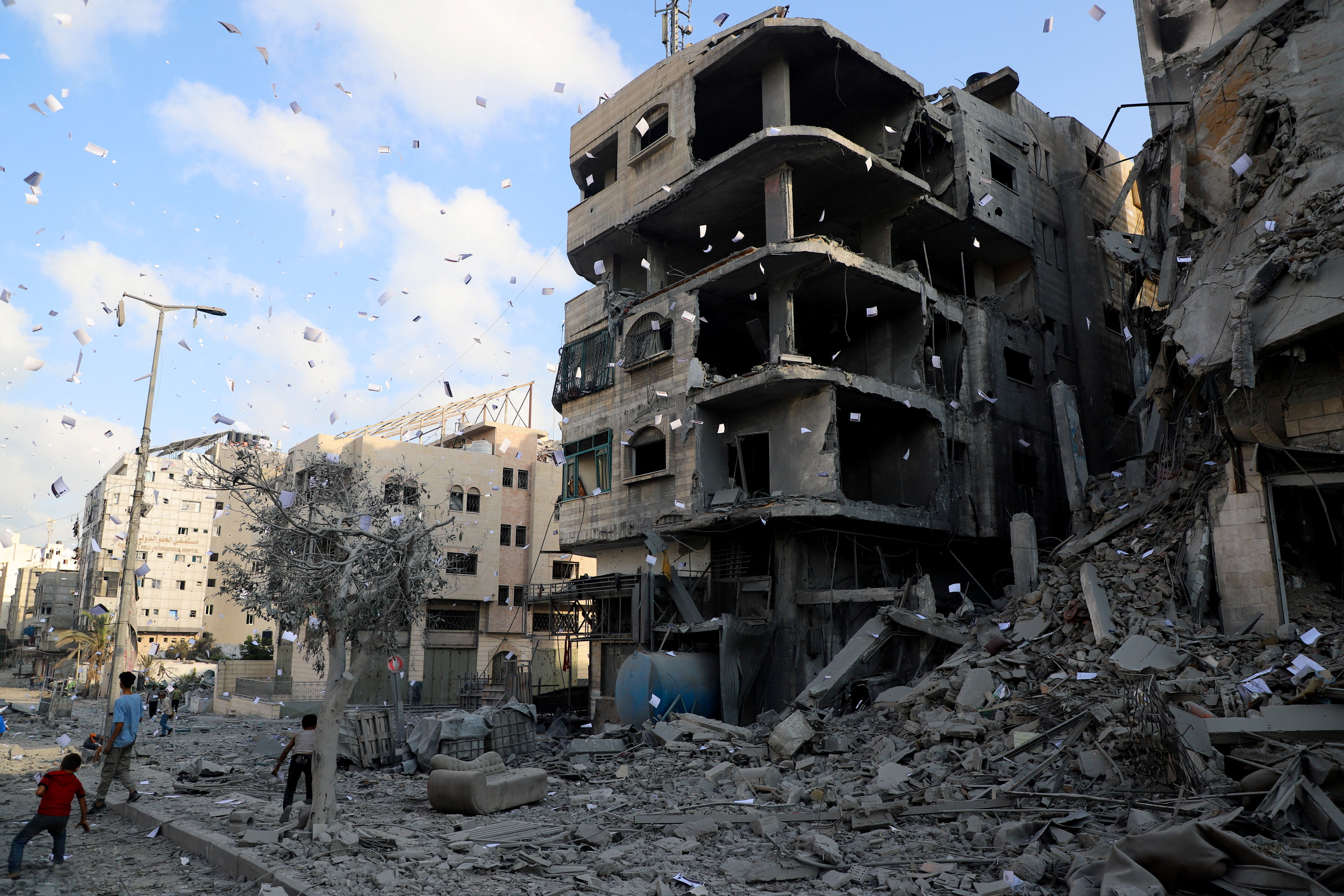 Leaflets that were dropped by Israeli forces, ordering residents of Gaza City to evacuate, fall next to a damaged building, in Gaza City, September 29, 2025. [Ebrahim Hajjaj/Reuters]