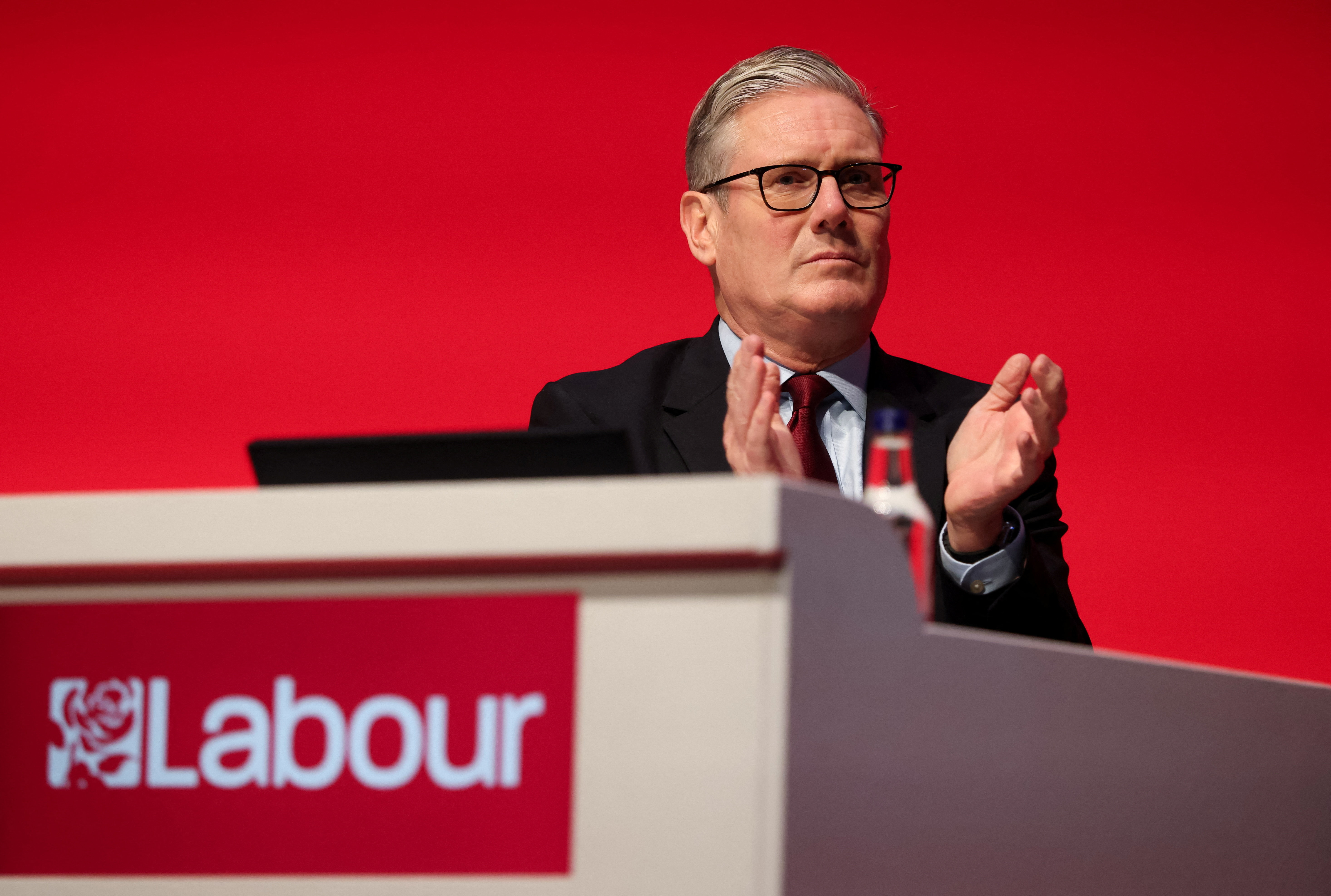 British Prime Minister Keir Starmer applauds at a podium.