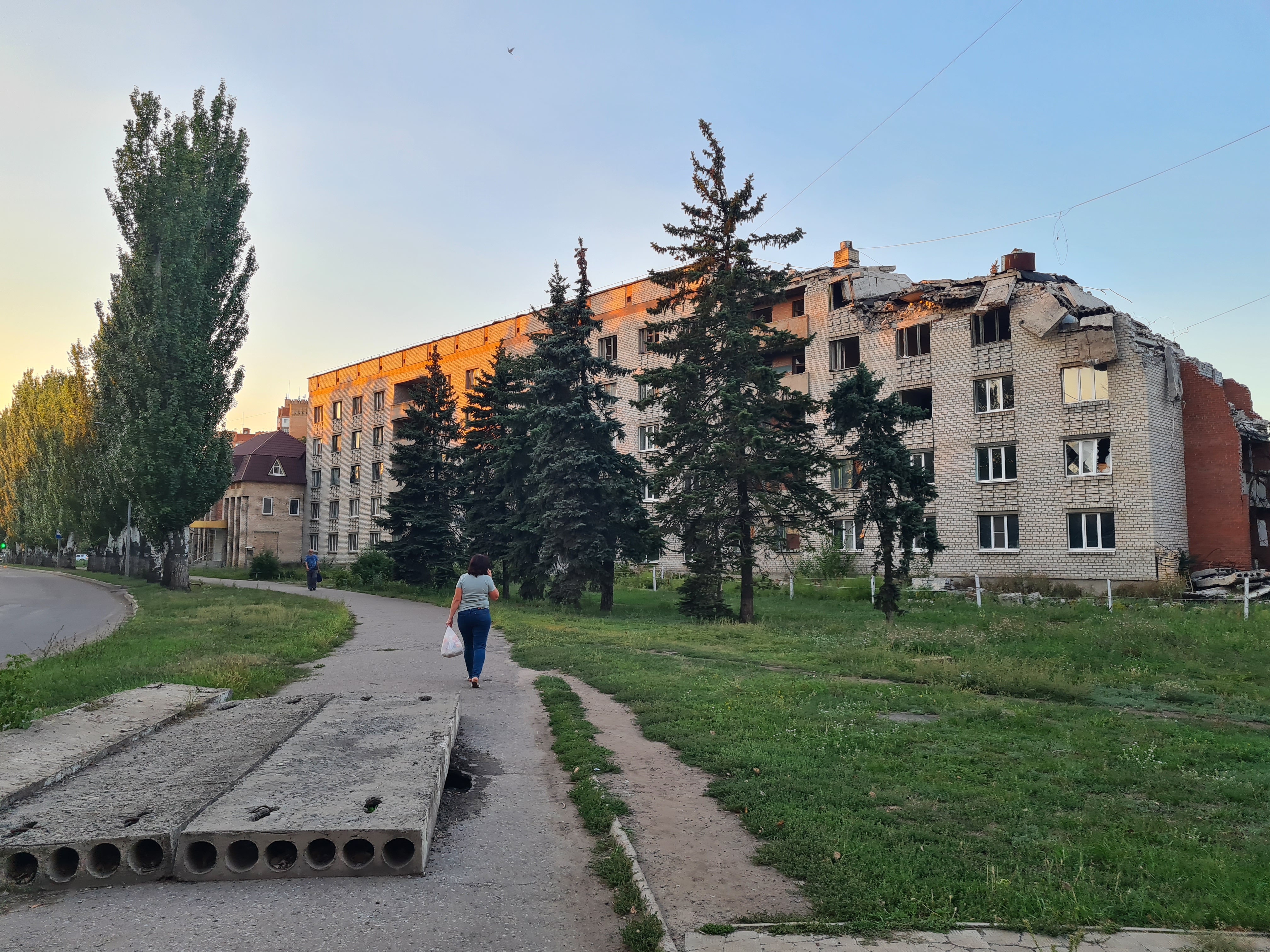 A resident of Slovyansk walks past a building damaged by Russian shelling-1758116295