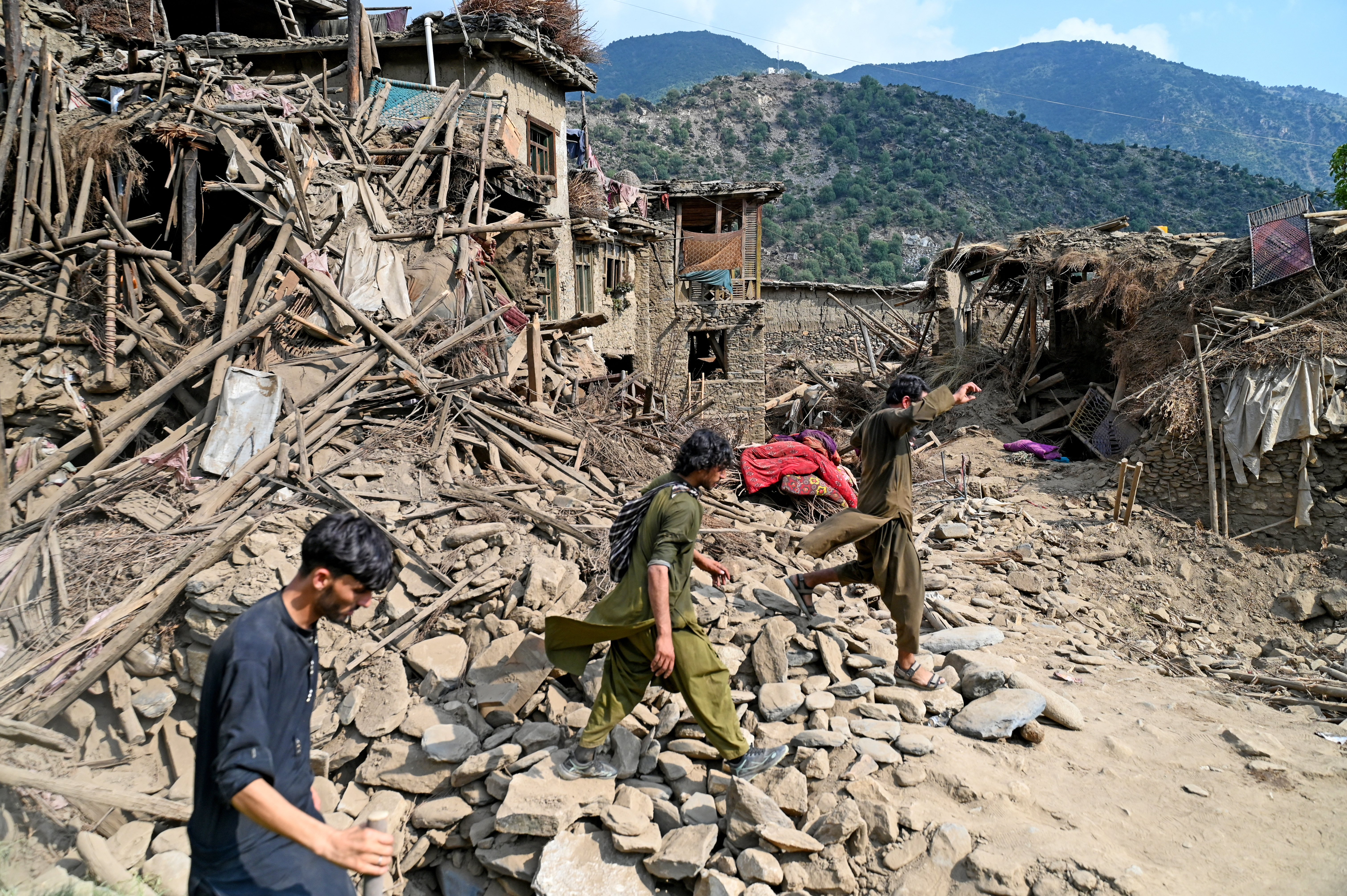 People walk past damaged houses after earthquakes.