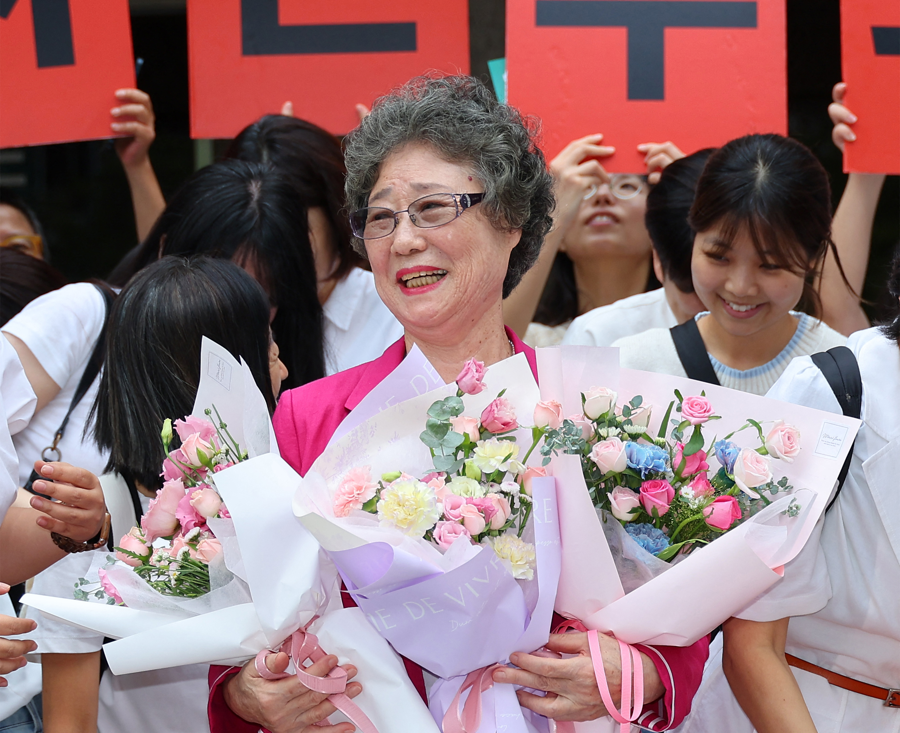 Choi Mal-ja (C) holds bouquets and smiles outside the court.