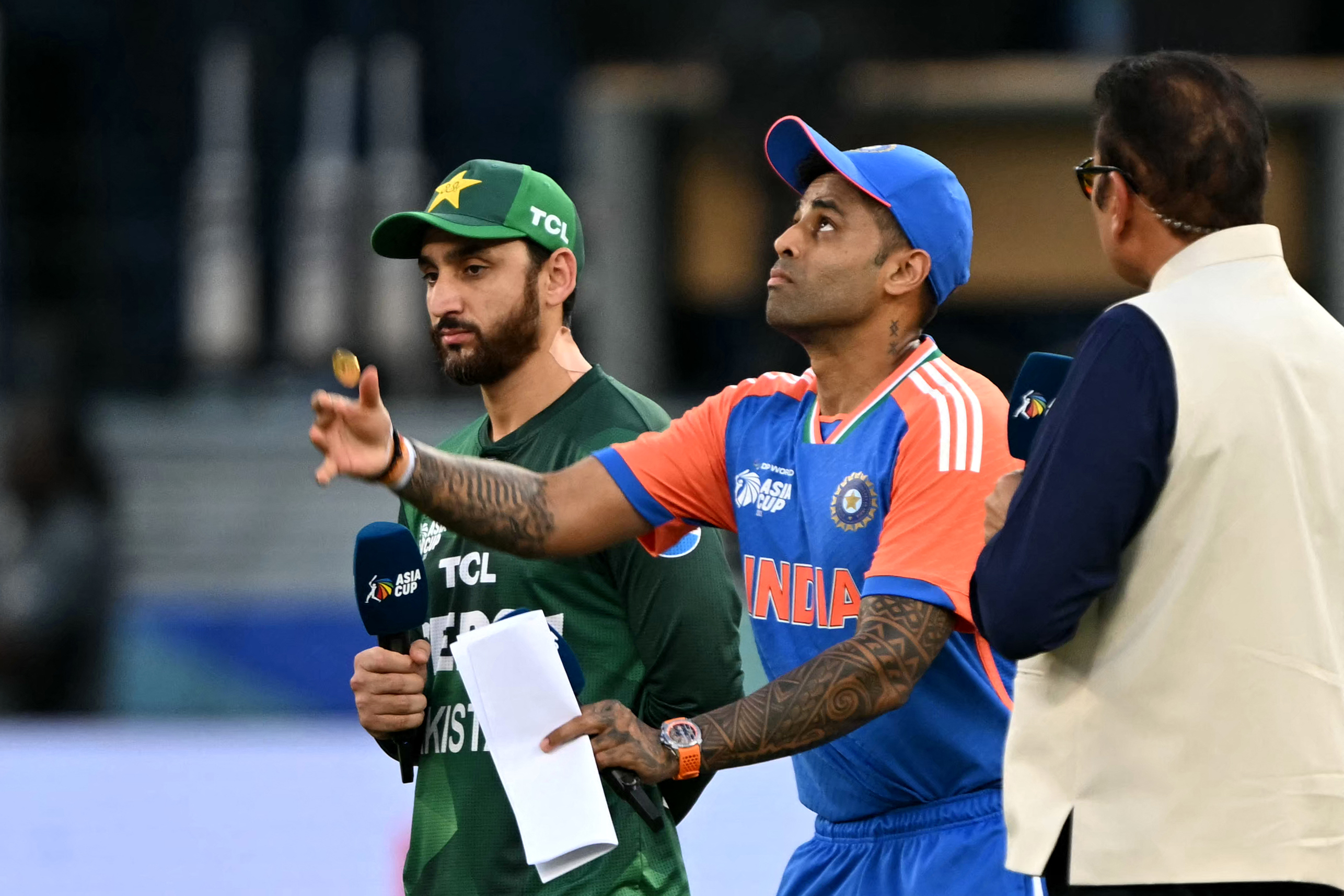 India's captain Suryakumar Yadav (C) tosses the coin at the start of the Asia Cup 2025 Twenty20 international cricket match between India and Pakistan at the Dubai International Stadium in Dubai on September 14, 2025. (Photo by Sajjad HUSSAIN / AFP)