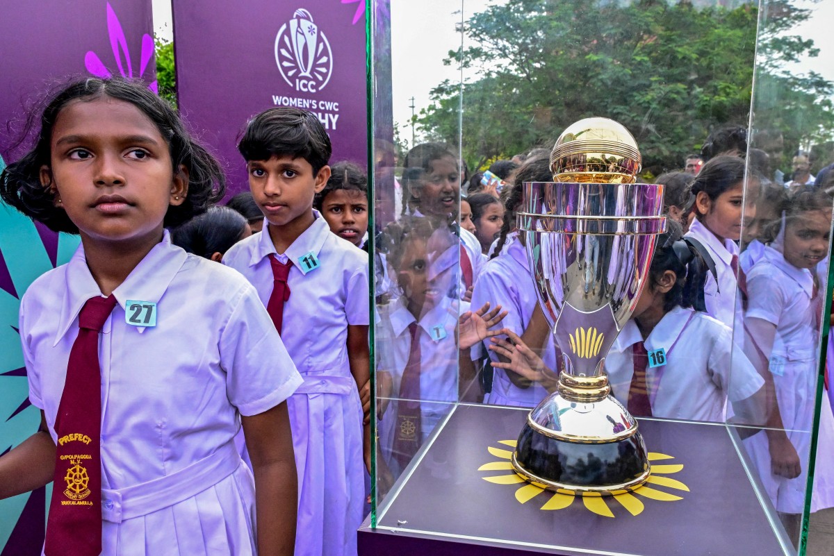 School children gather around the 2025 ICC Women's Cricket World Cup Trophy on public display at the outside of the Colombo Lotus Tower in Colombo on September 24, 2025. (Photo by Ishara S. KODIKARA / AFP)