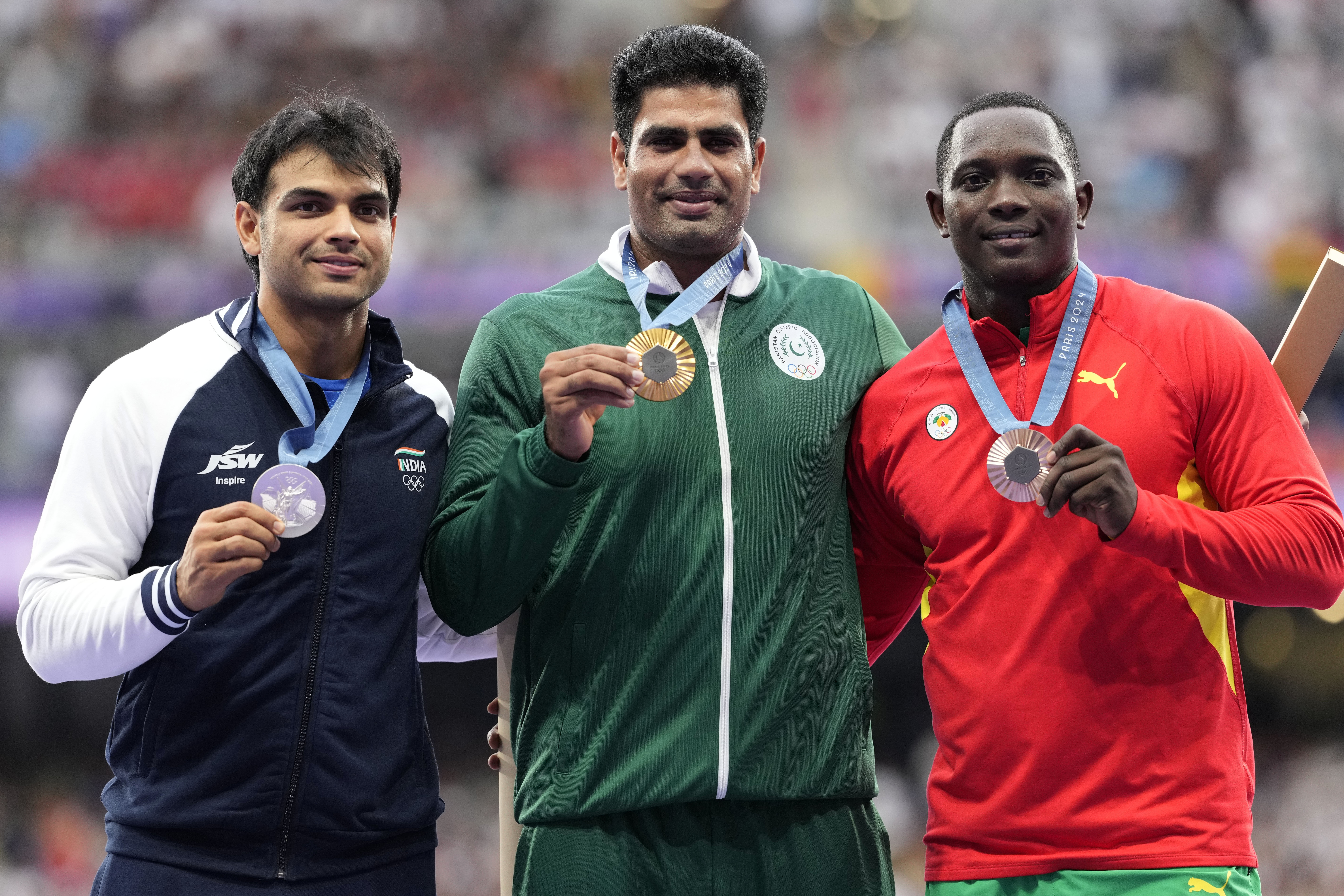 Men's javelin gold medalist, Arshad Nadeem, centre, of Pakistan, stands with silver medalist, Neeraj Chopra, of India, and bronze medalist, Anderson Peters, right, of Grenada, on the podium at the 2024 Summer Olympics, Friday, Aug. 9, 2024, in Saint-Denis, France. (AP Photo/Bernat Armangue)