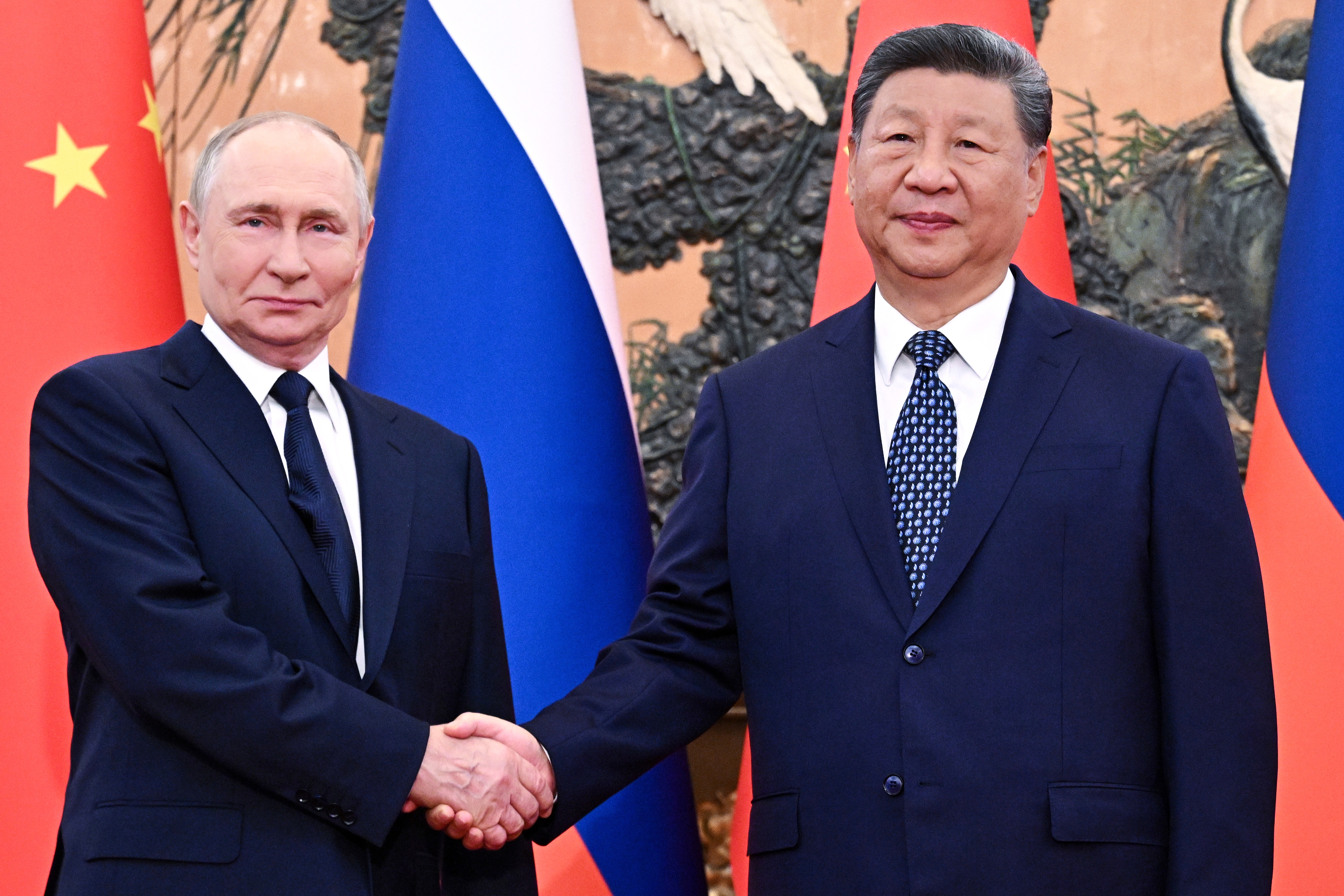 Russian President Vladimir Putin, left, and Chinese President Xi Jinping shake hands.