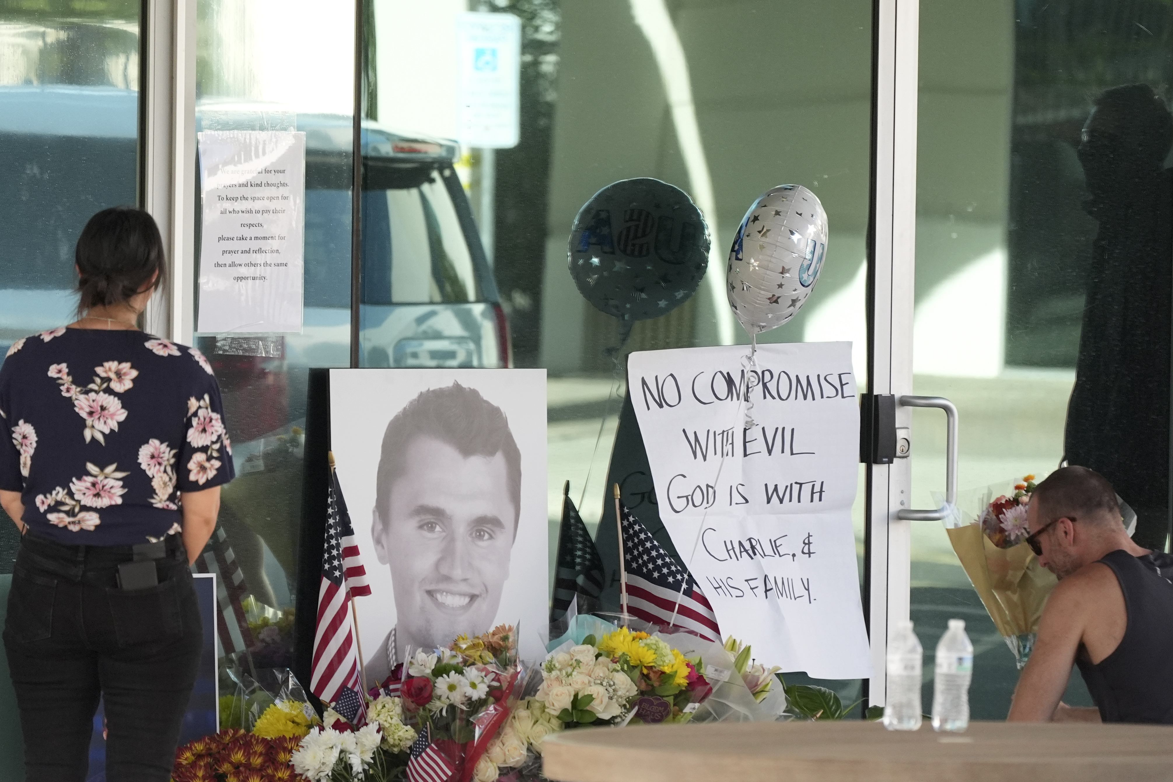 Well-wishers pay their respects at a makeshift memorial at the national headquarters of Turning Point USA shown after the shooting death of Charlie Kirk, the co-founder and CEO of the organization, during a Utah college event Wednesday, Sept. 10, 2025, in Phoenix. (AP Photo/Ross D. Franklin)