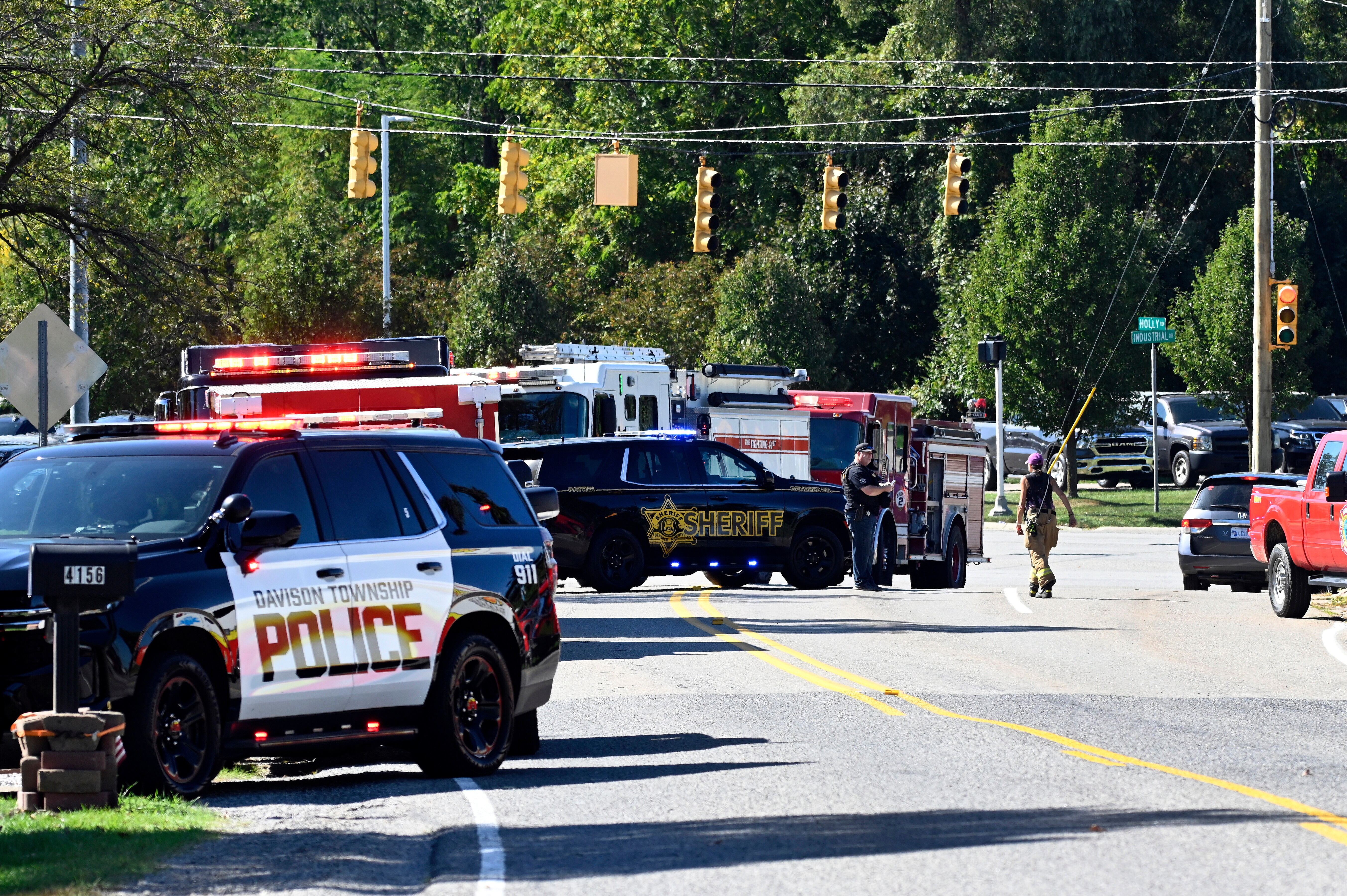 Law enforcement and fire personnel stand near the corner of McCandlish and Holly road, near a shooting site