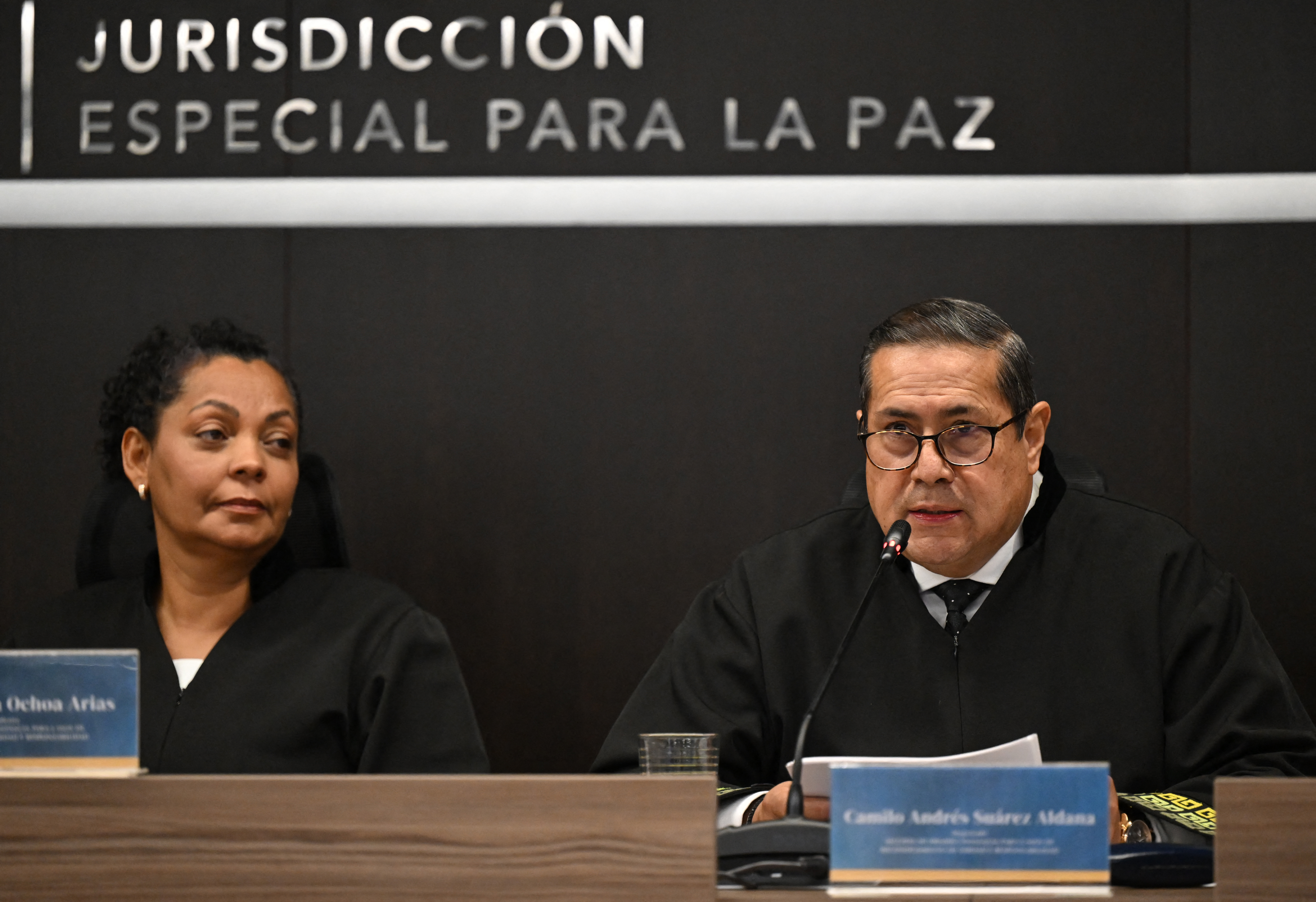 Special Jurisdiction of Peace (JEP) magistrate Camilo Suarez speaks as magistrate Ana Ochoa listens at the sentence hearing of former FARC guerrilla leaders over kidnapping crimes committed during the Colombian armed conflict, at the JEP headquarters in Bogota on September 16, 2025.
