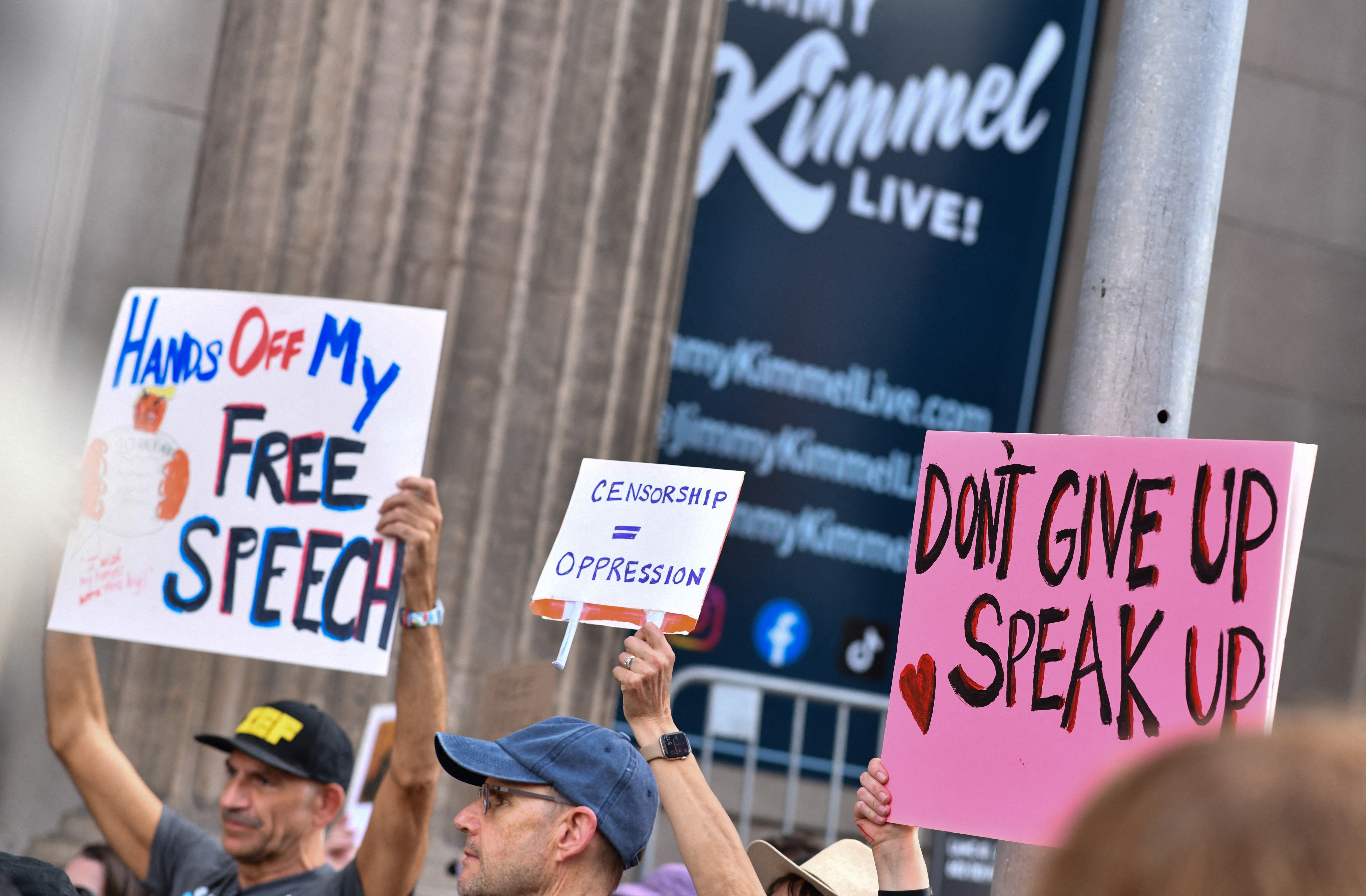 Demonstrators hold signs as they rally to protest.
