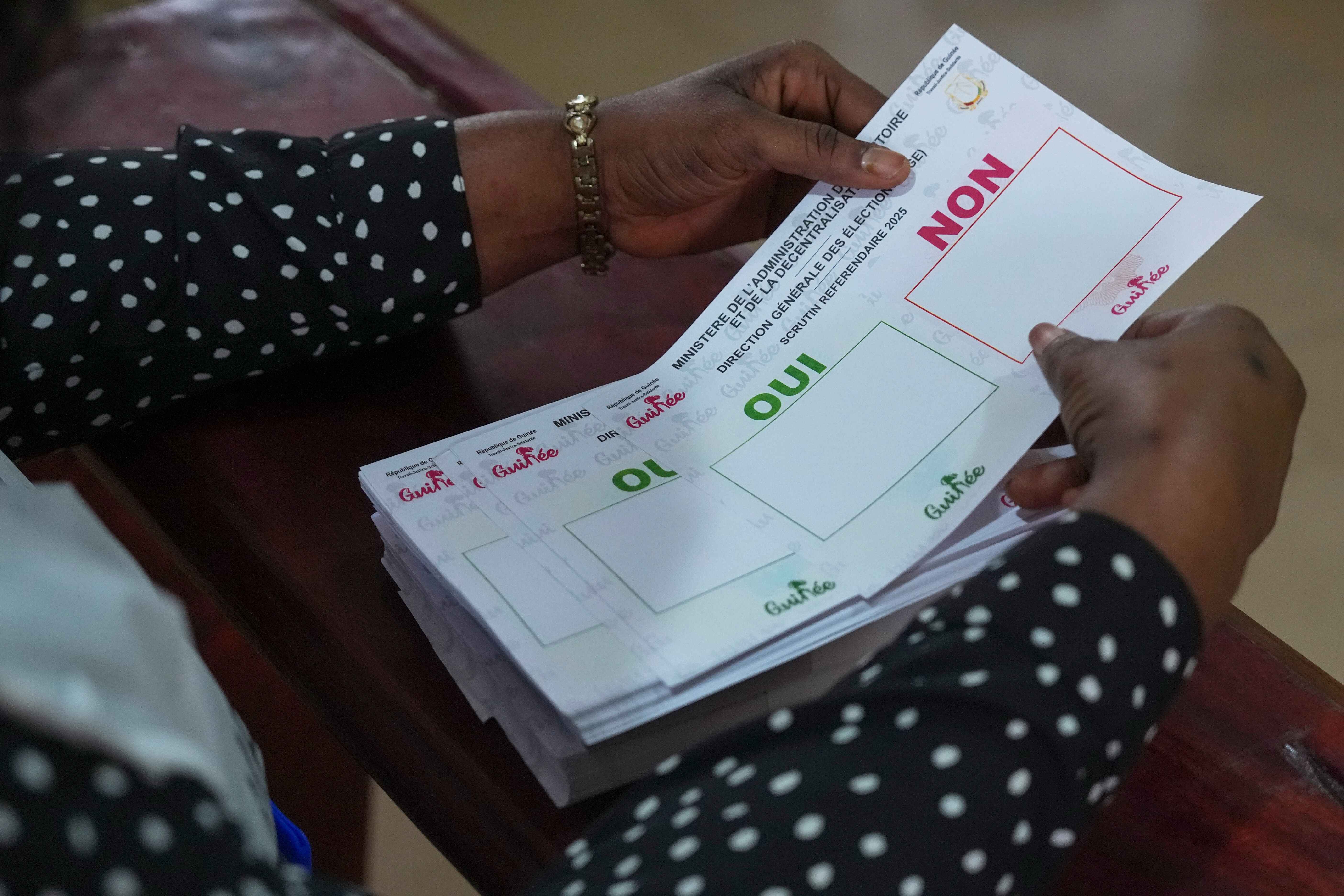A polling official holds referendum ballots at a polling station, in Conakry, Guinea, Sunday, Sept. 21, 2025. (AP Photo/Misper Apawu)