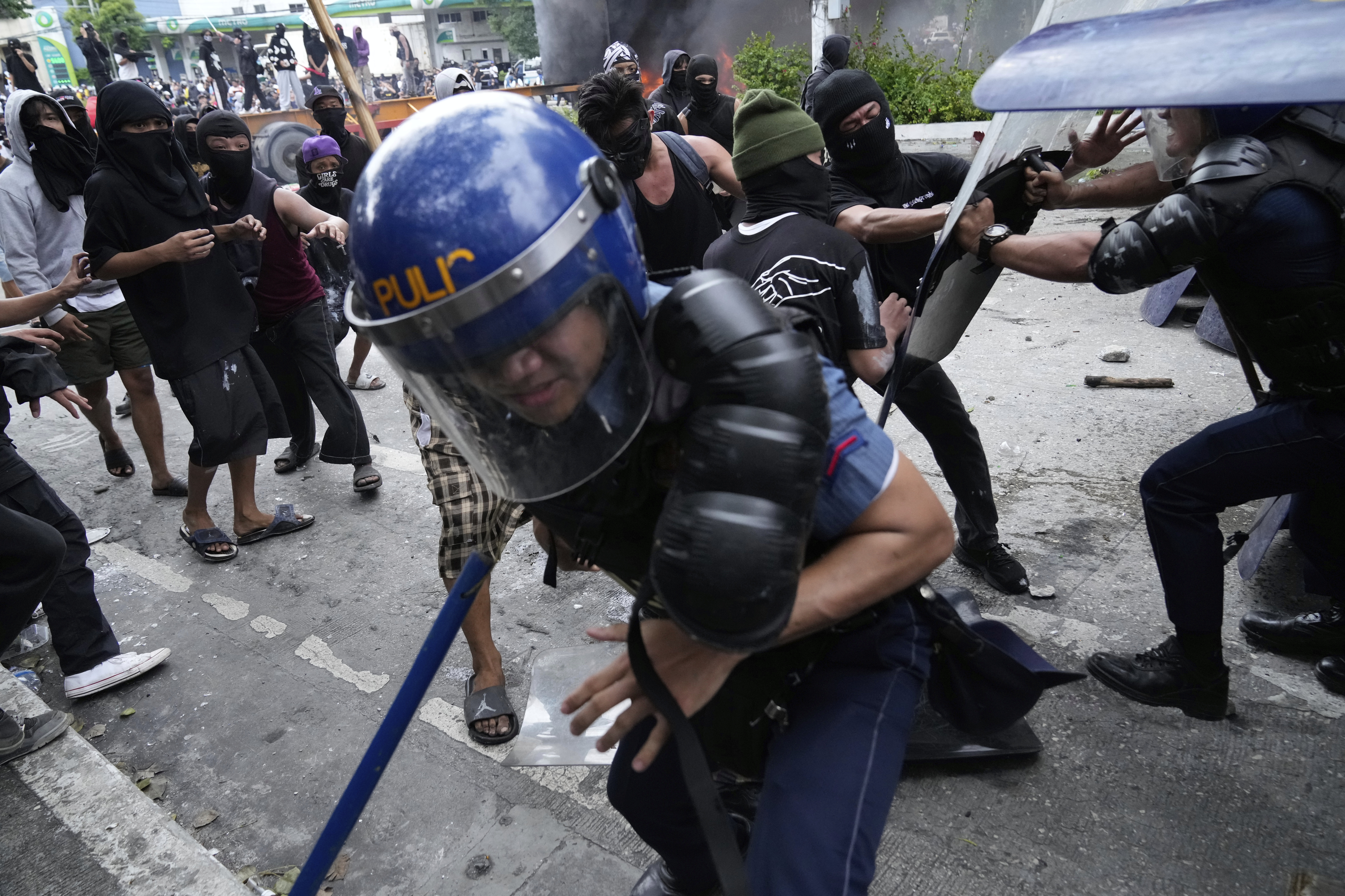 Police escape protesters during a scuffle as they tried to enter the Malacanang presidential palace compound in Manila, Philippines
