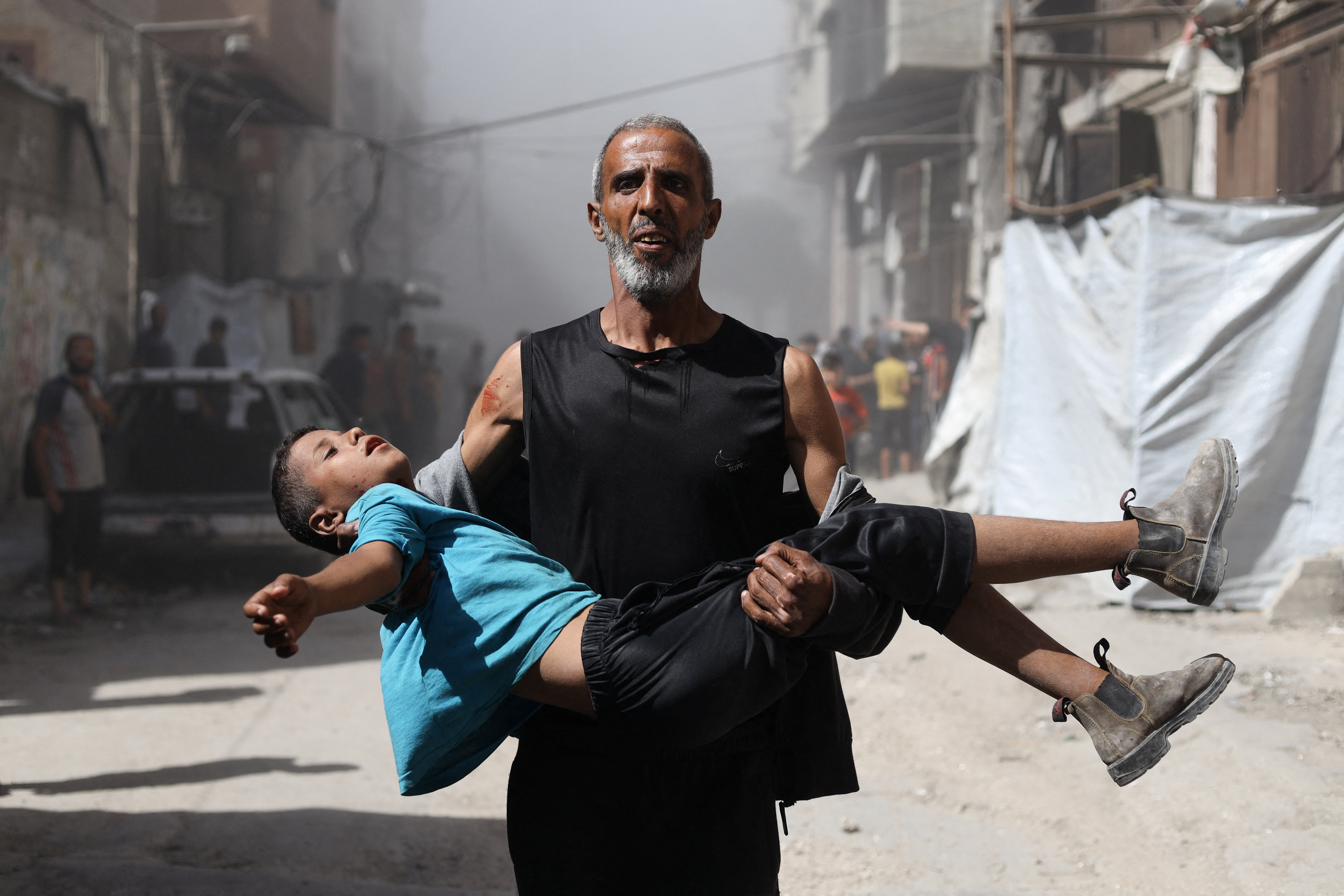 A Palestinian man carries a wounded child after an Israeli airstrike on a house, in Gaza City, September 7, 2025. REUTERS/Khamis Al-Rifi