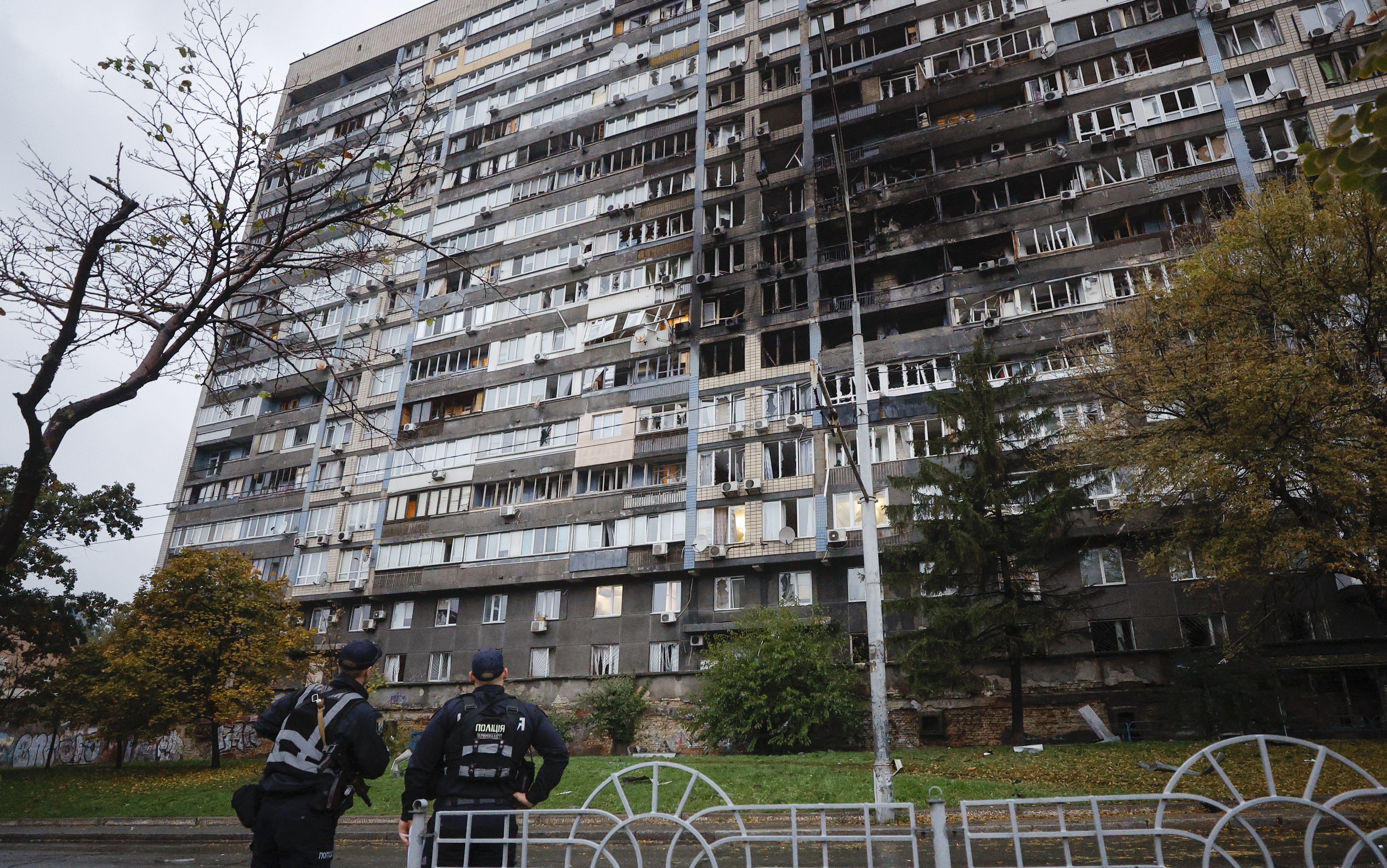 Ukrainian policemen stand near a damaged residential building after a Russian strike in Kyiv, Ukraine on October 10, 2025.