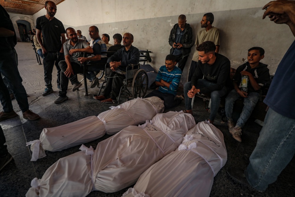 Palestinian relatives of the Abu Shaban family stand around the bodies of their loved ones at al-Ahli Hospital in Gaza