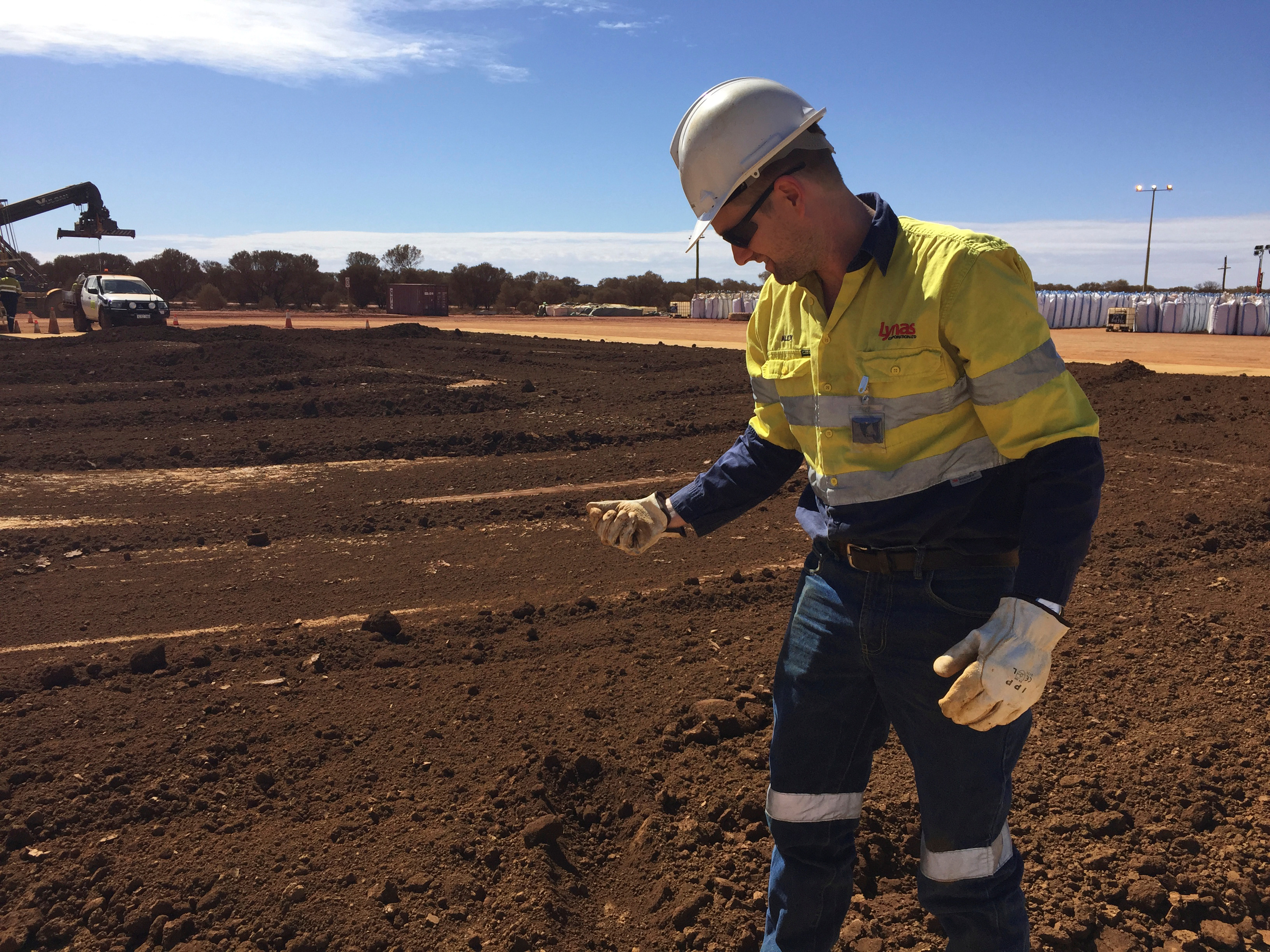 A worker picks up a handful of rare earth concentrate that has been left to dry in the sun before it is packed and shipped to Malaysia for further processing, at Mount Weld, northeast of Perth, Australia [File: Melanie Burton/Reuters]