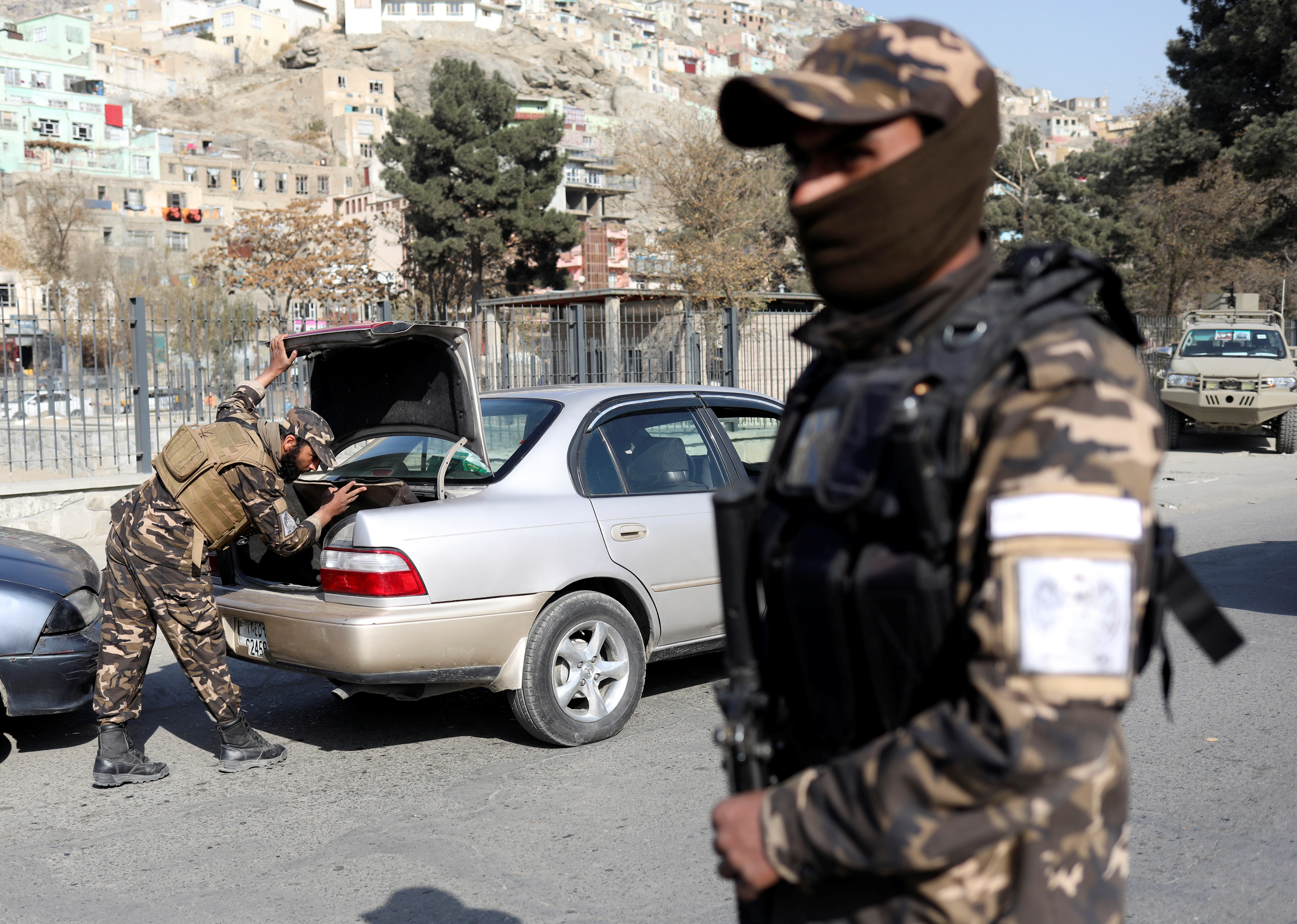 A Taliban fighter searches a car as they hold a checkpoint.