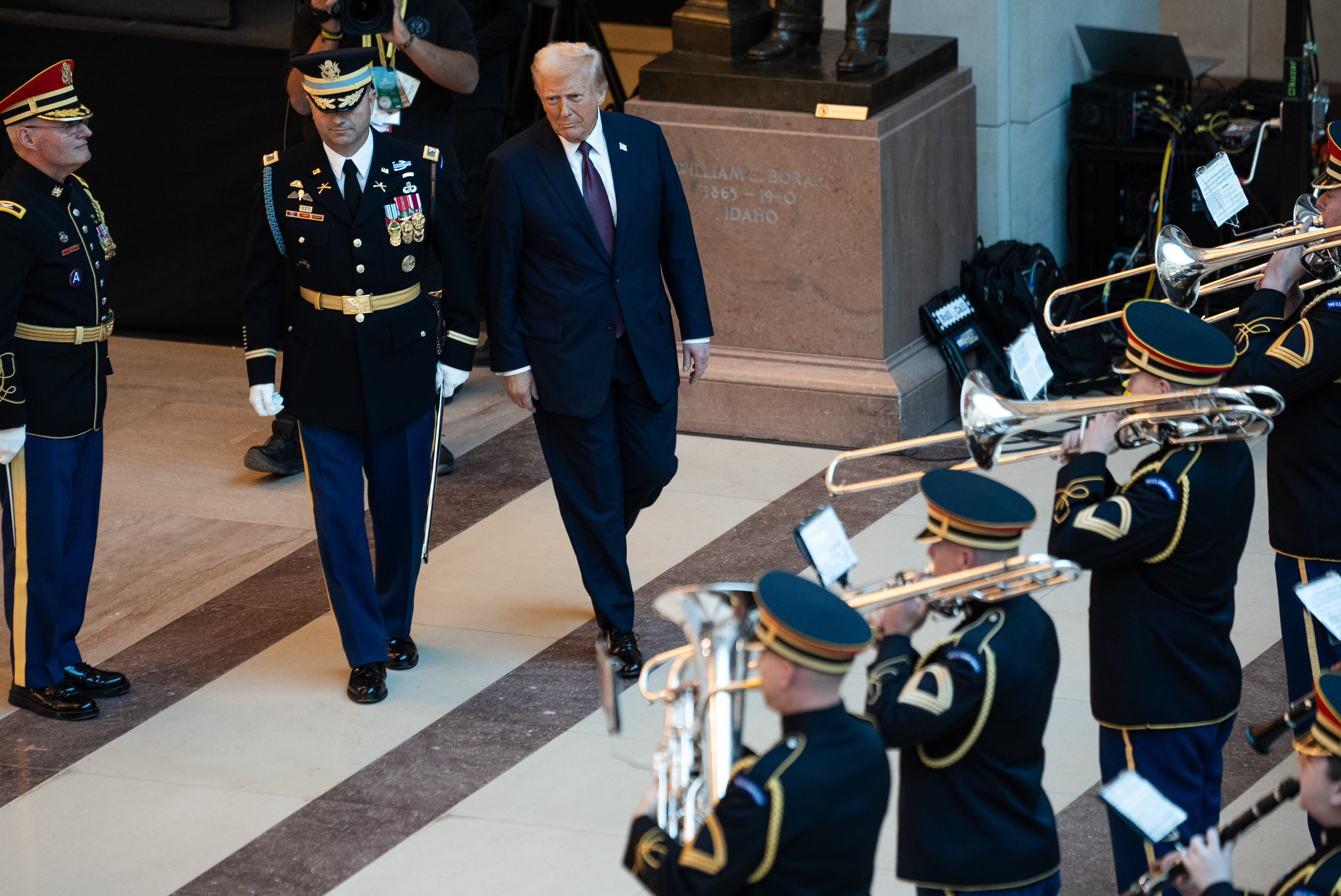 Donald Trump walks past a military band